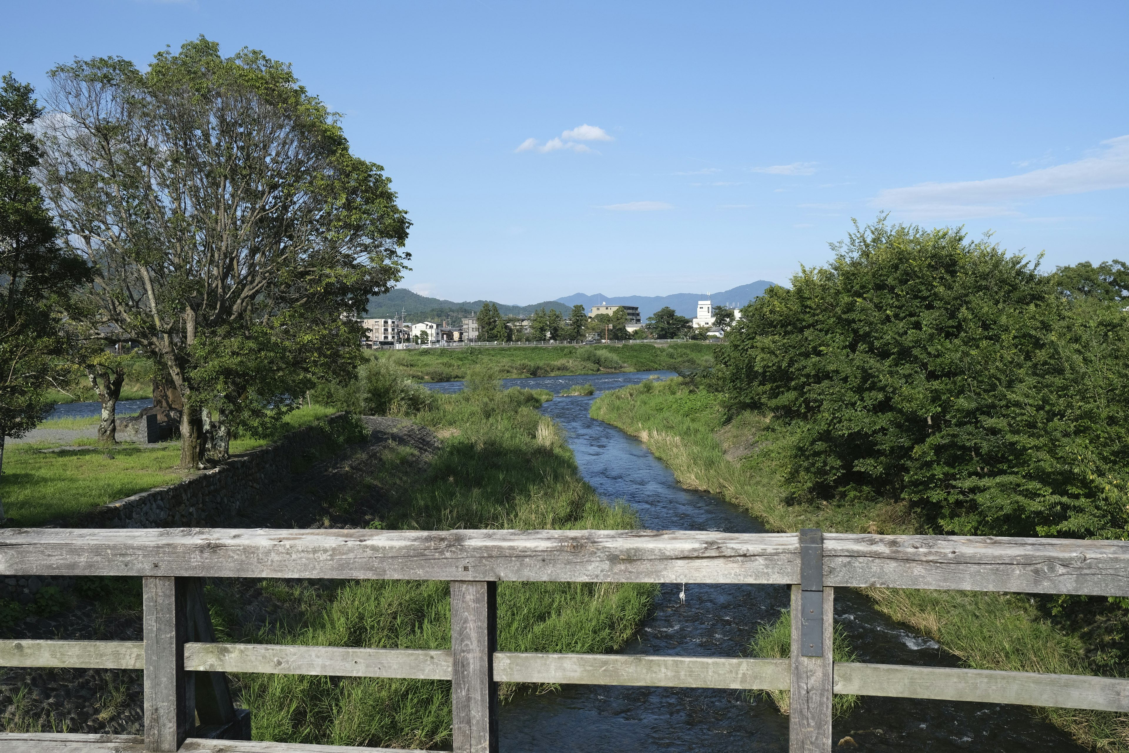 Vue depuis un pont en bois sur une rivière et un paysage verdoyant