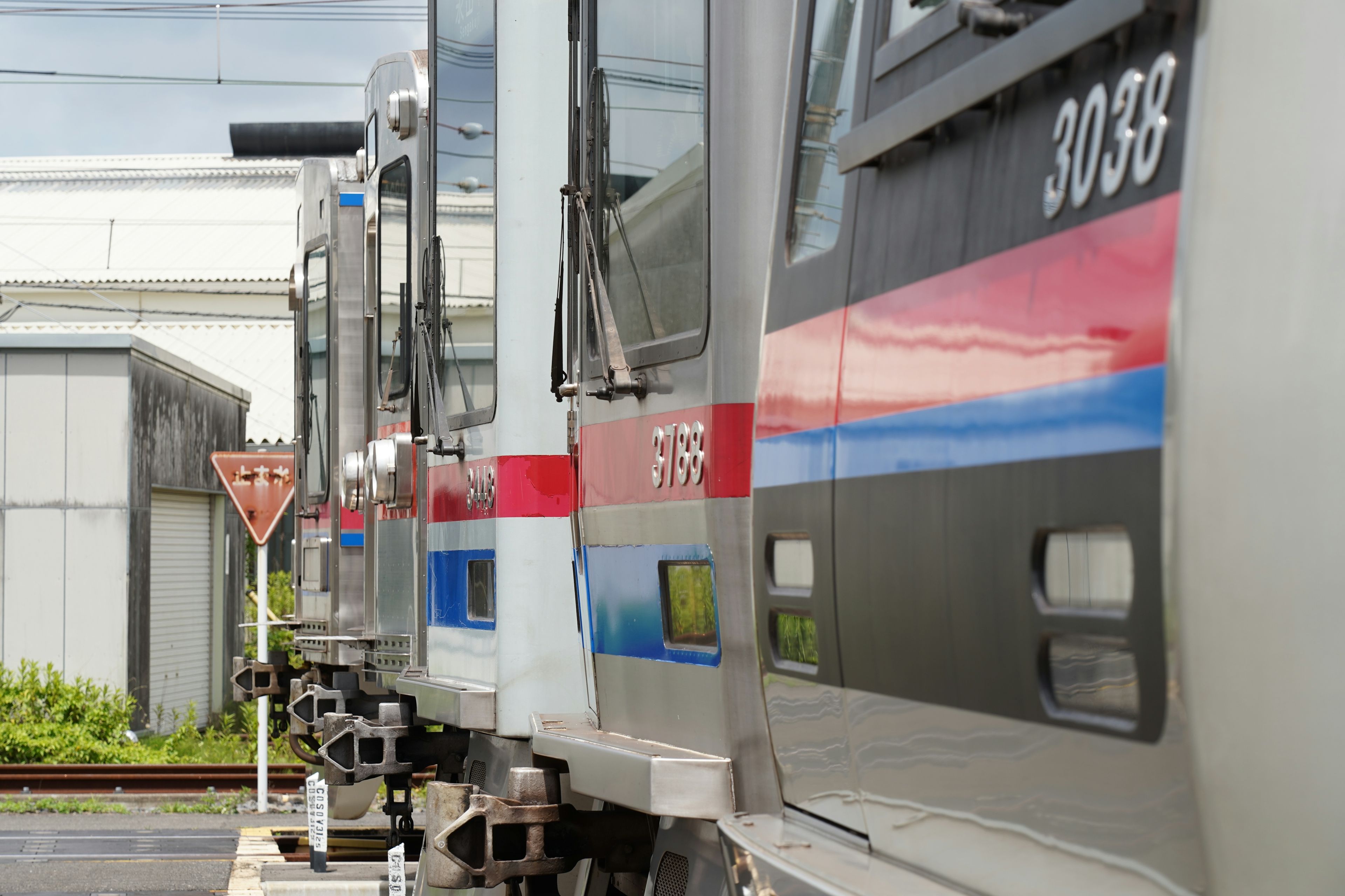 Side view of trains lined up at a railway station featuring train number 3038