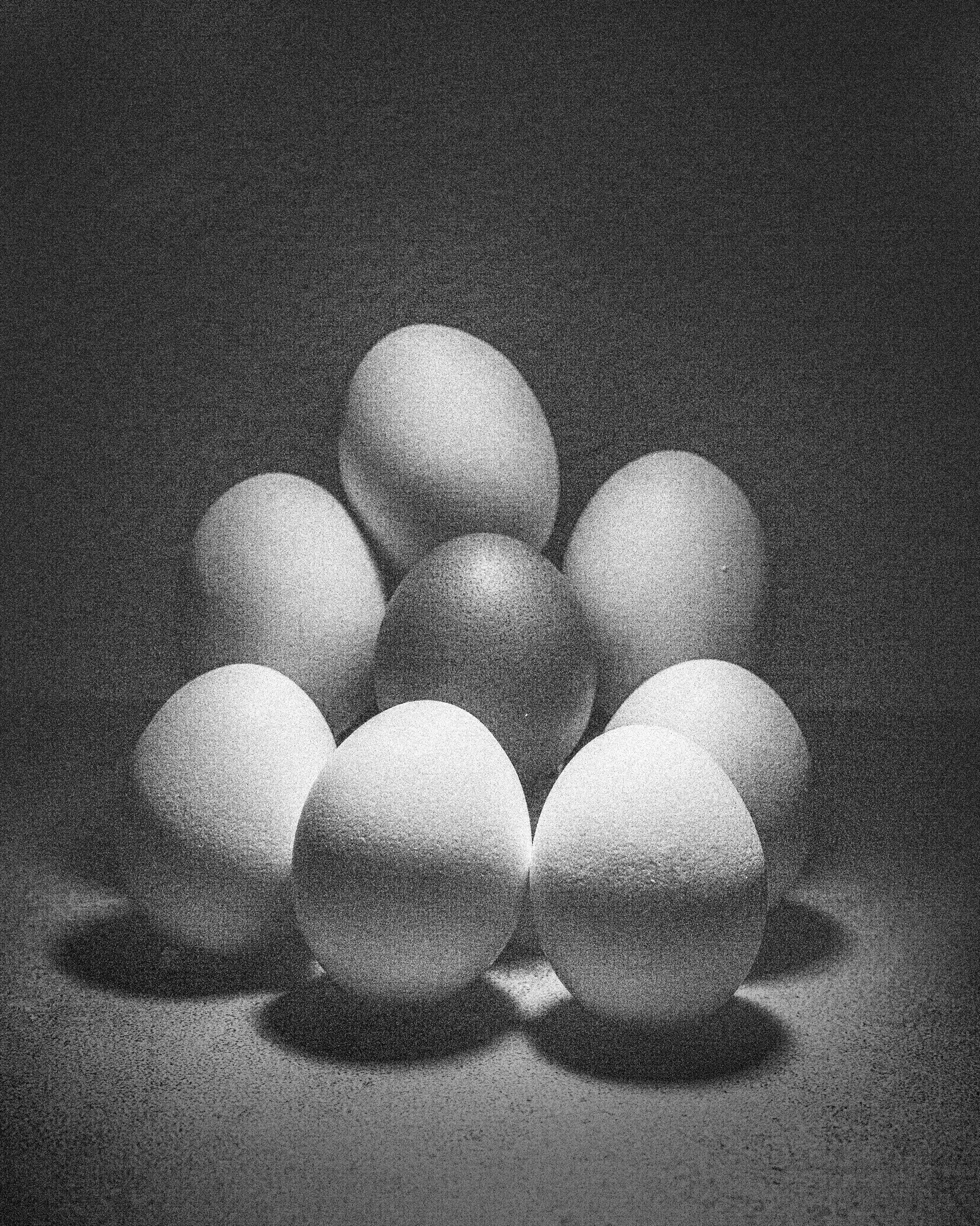 A monochrome image of white eggs arranged in a triangular formation