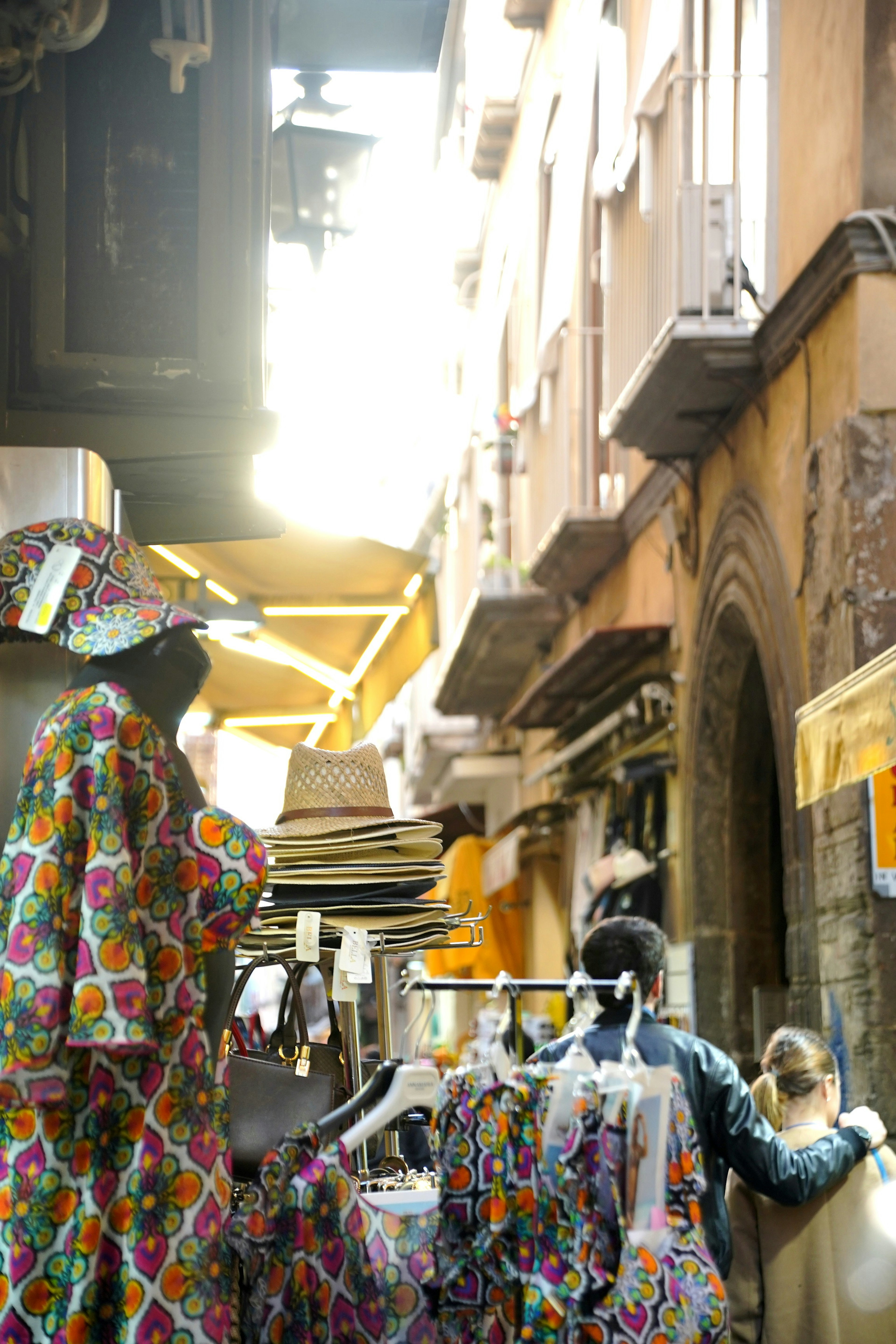 Scena di una strada stretta con abbigliamento colorato esposto e luce solare che entra