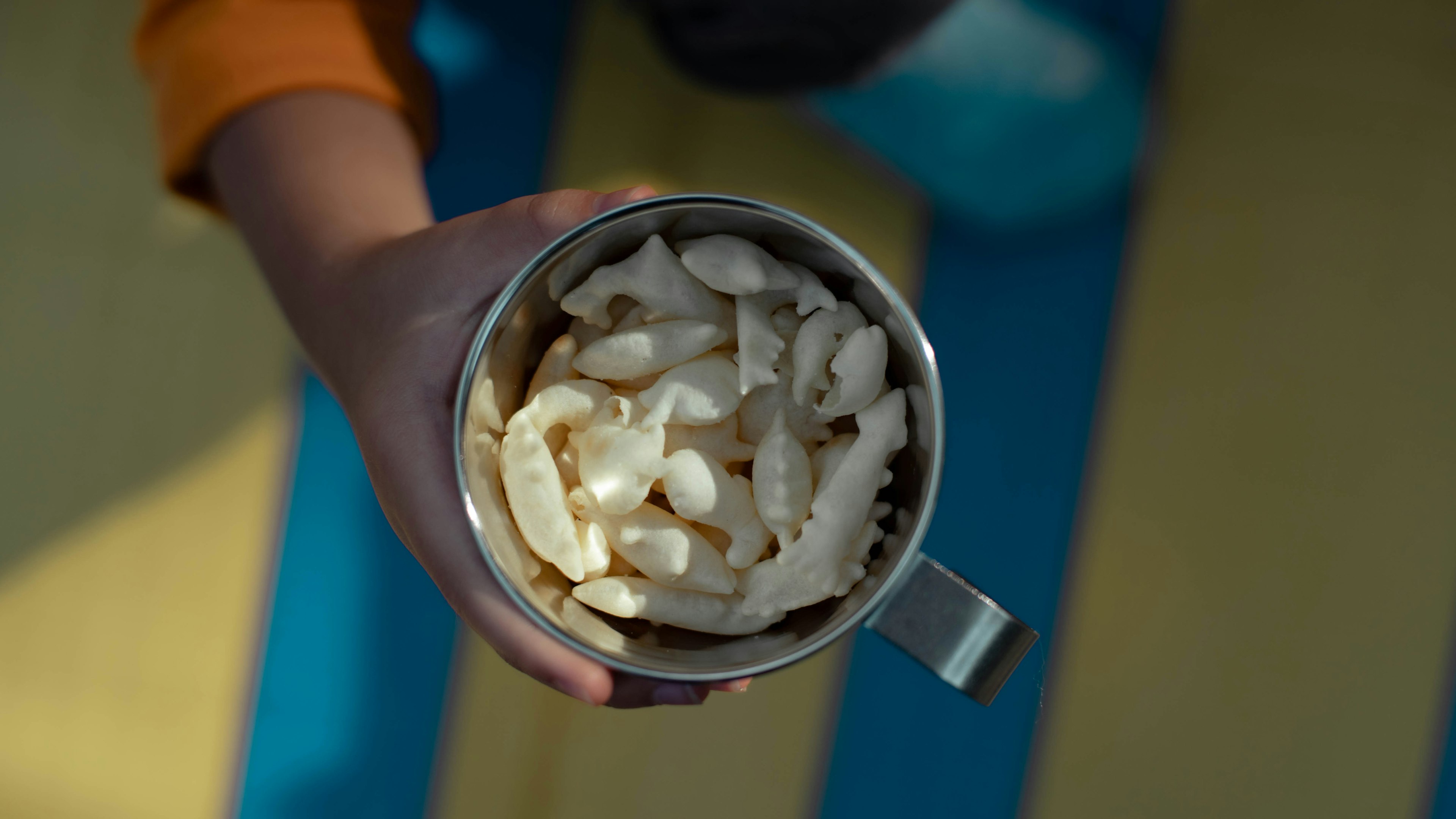 Child holding a silver cup filled with white snacks