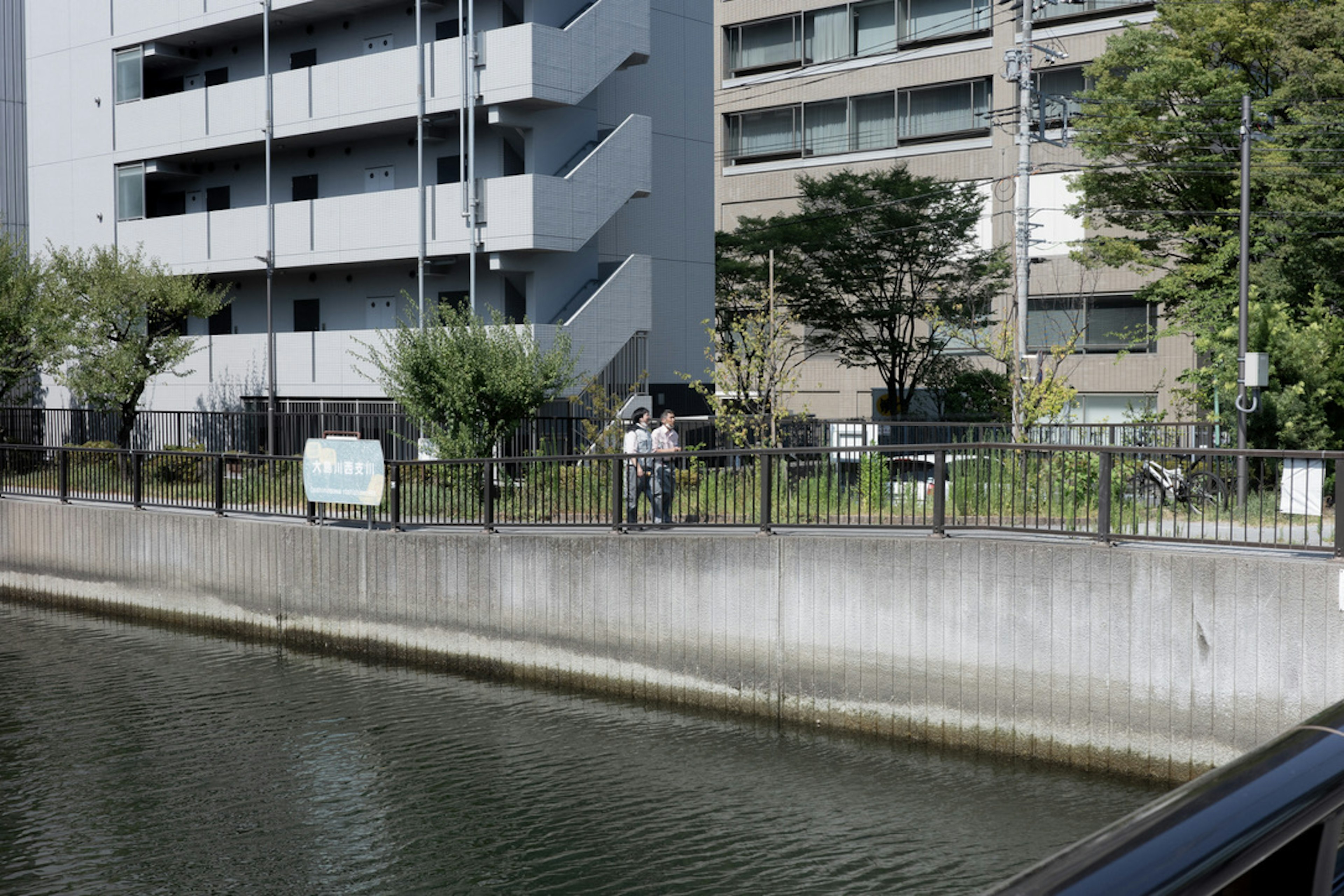 川のほとりに立つ人と近代的な建物の景色