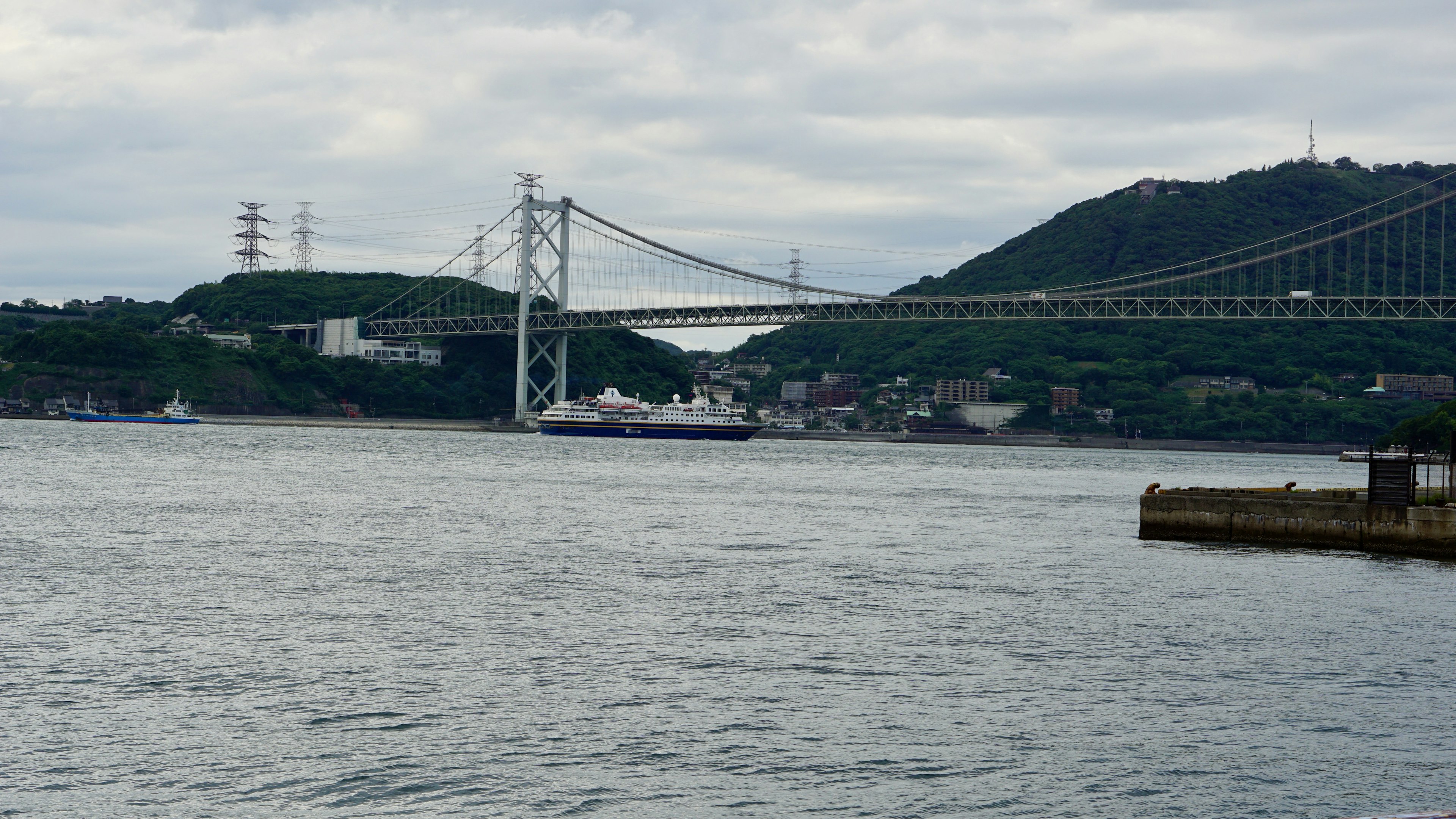 A scenic view of a bridge over water with a ship in the foreground