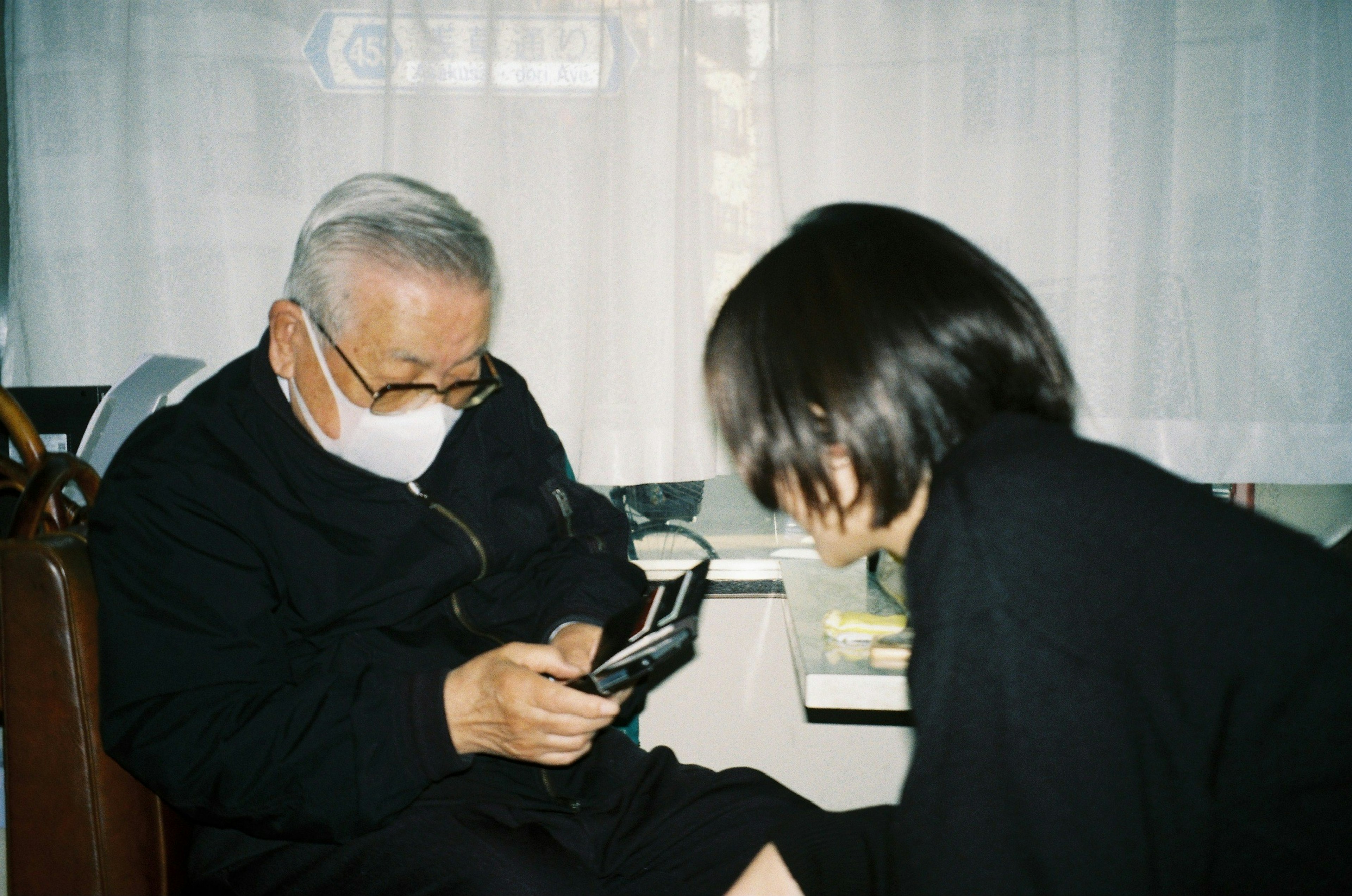 Hombre anciano con mascarilla usando un teléfono inteligente en un entorno acogedor