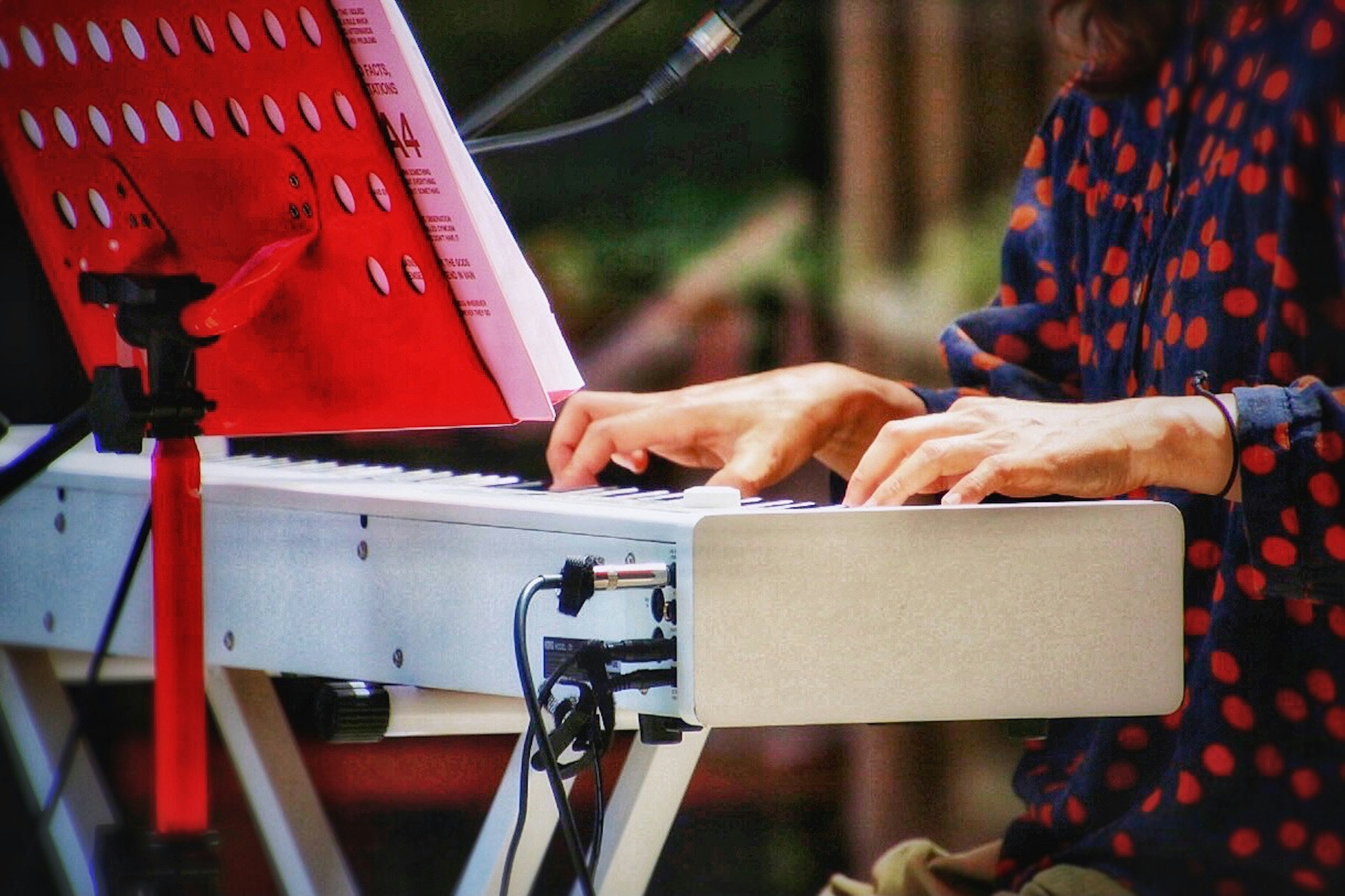 Person in a red polka dot shirt playing a keyboard