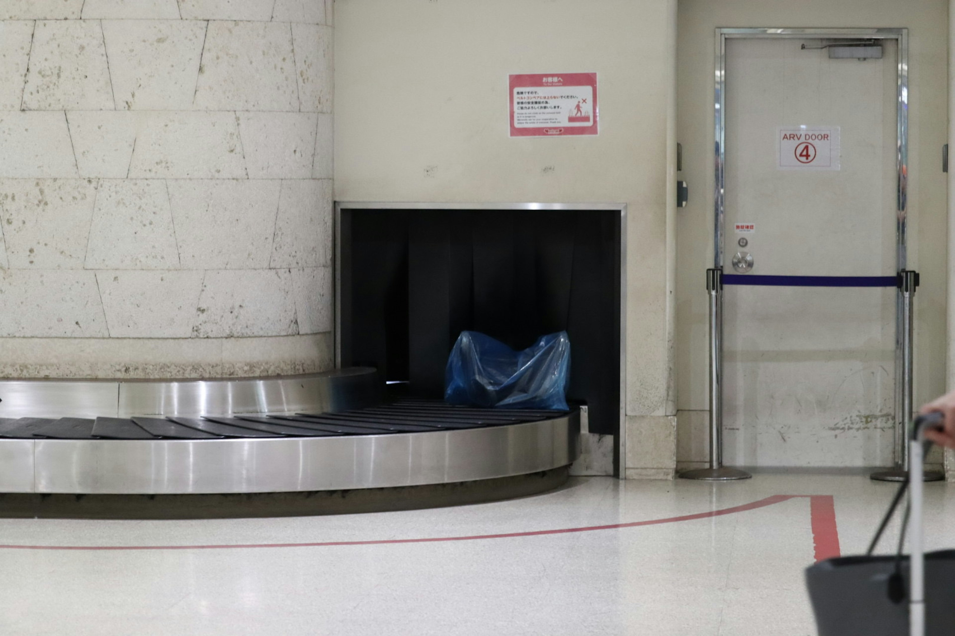 Airport baggage claim area with conveyor belt and blue plastic bag