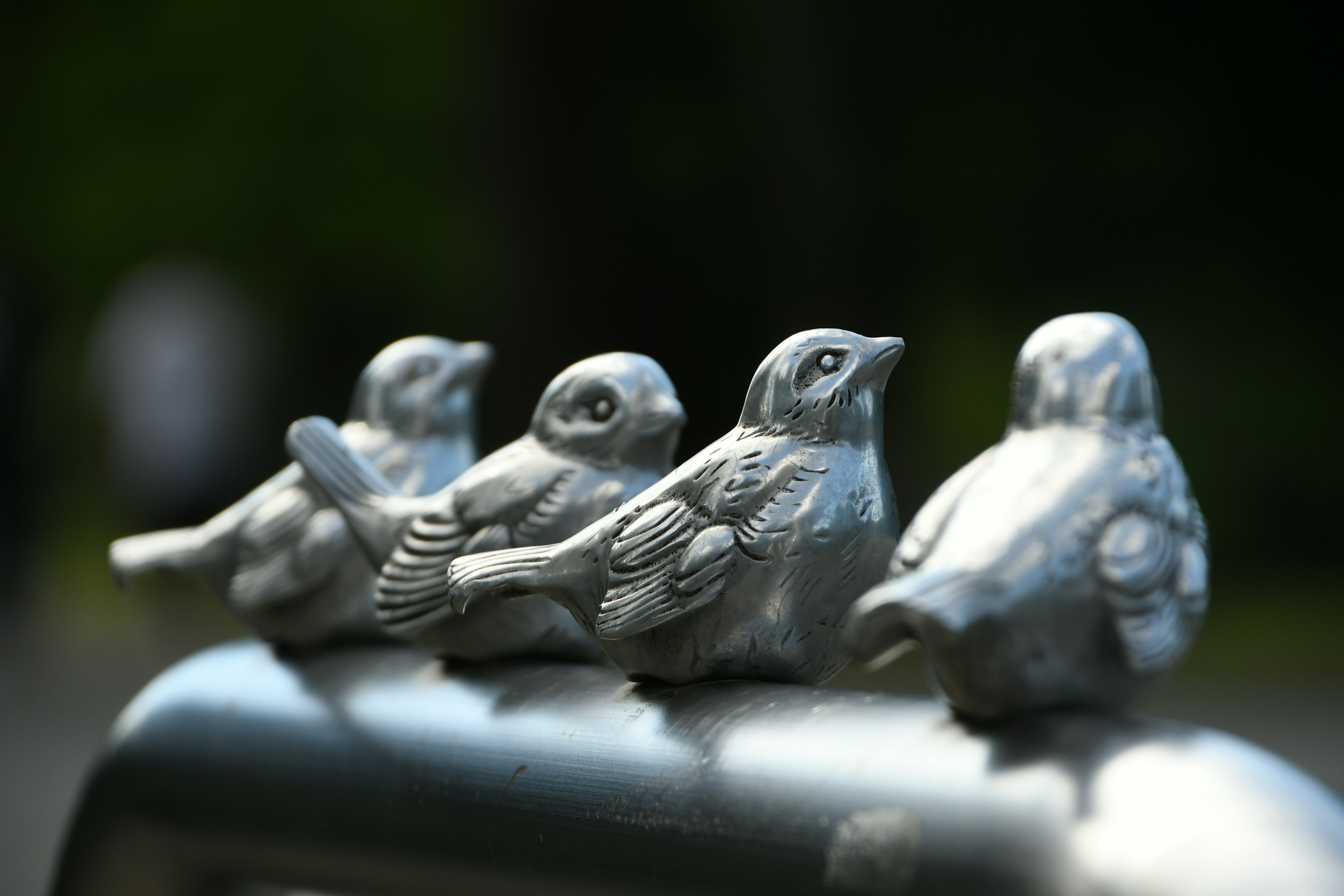 Row of metal bird sculptures perched on a railing