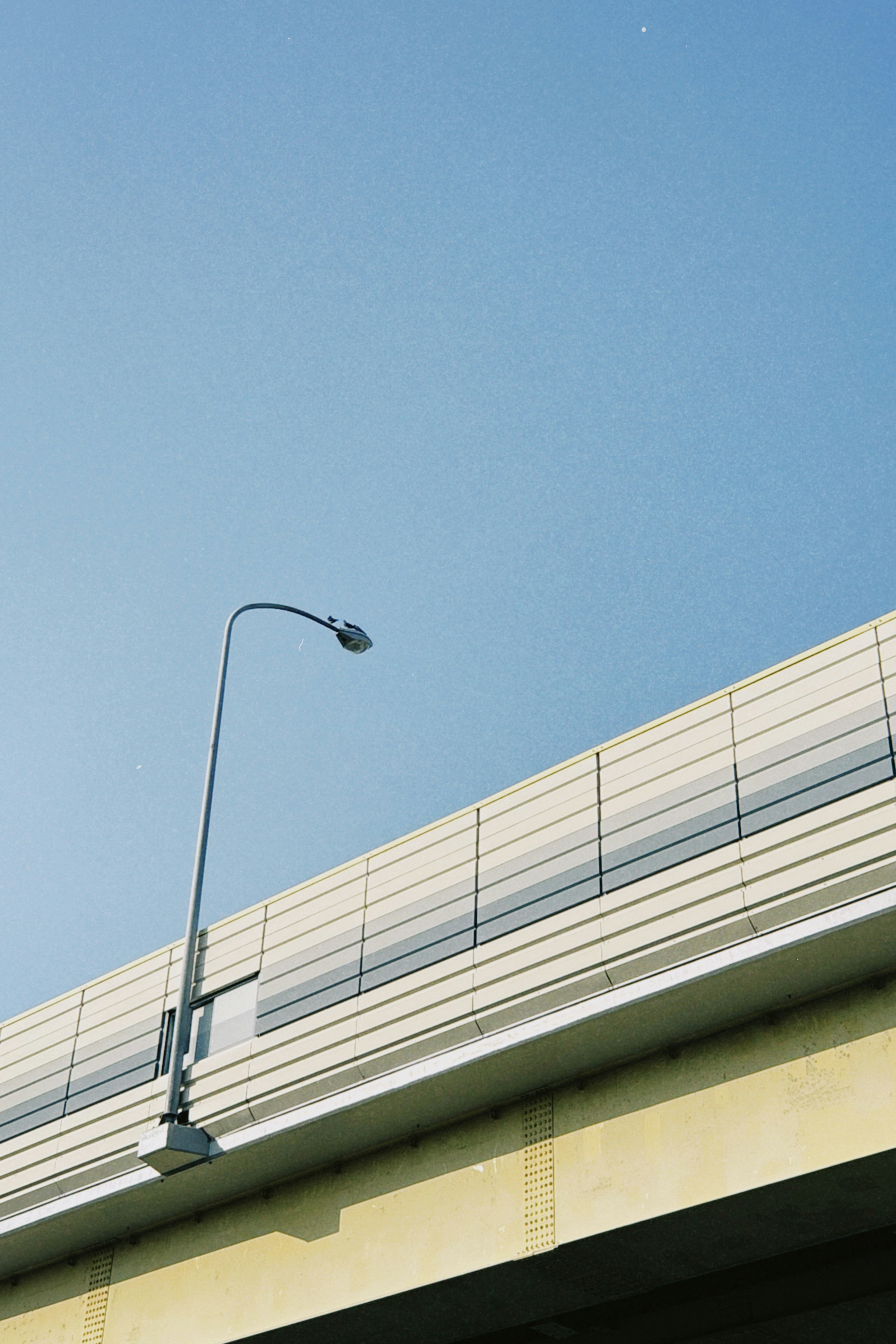 Photo of an elevated bridge with a streetlight under a clear blue sky