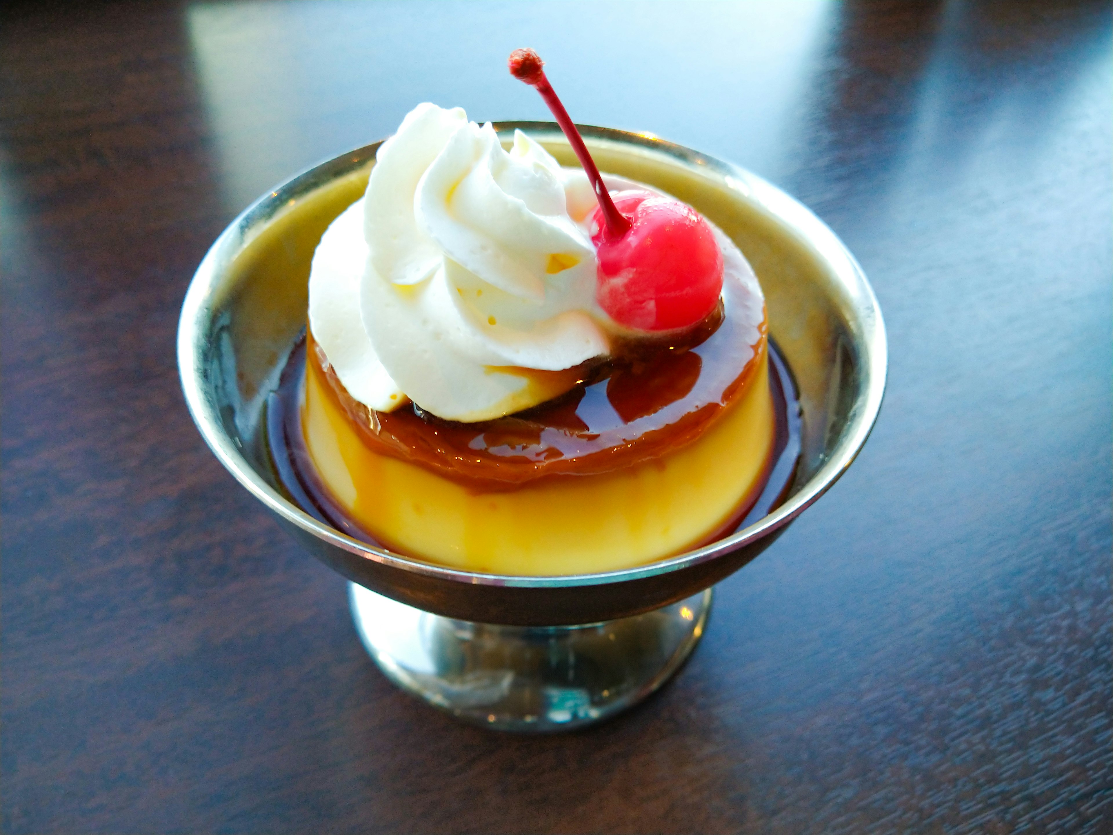 Custard pudding topped with cream and a cherry