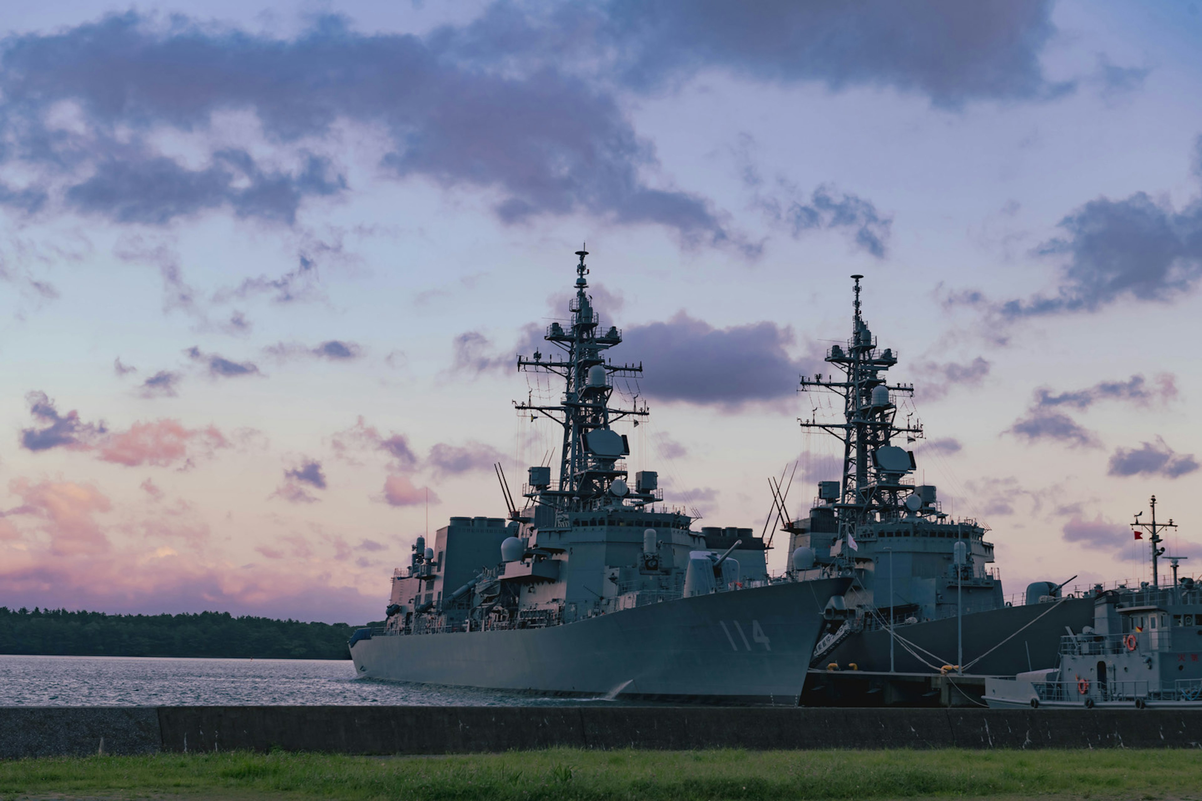 Warships docked against a sunset sky