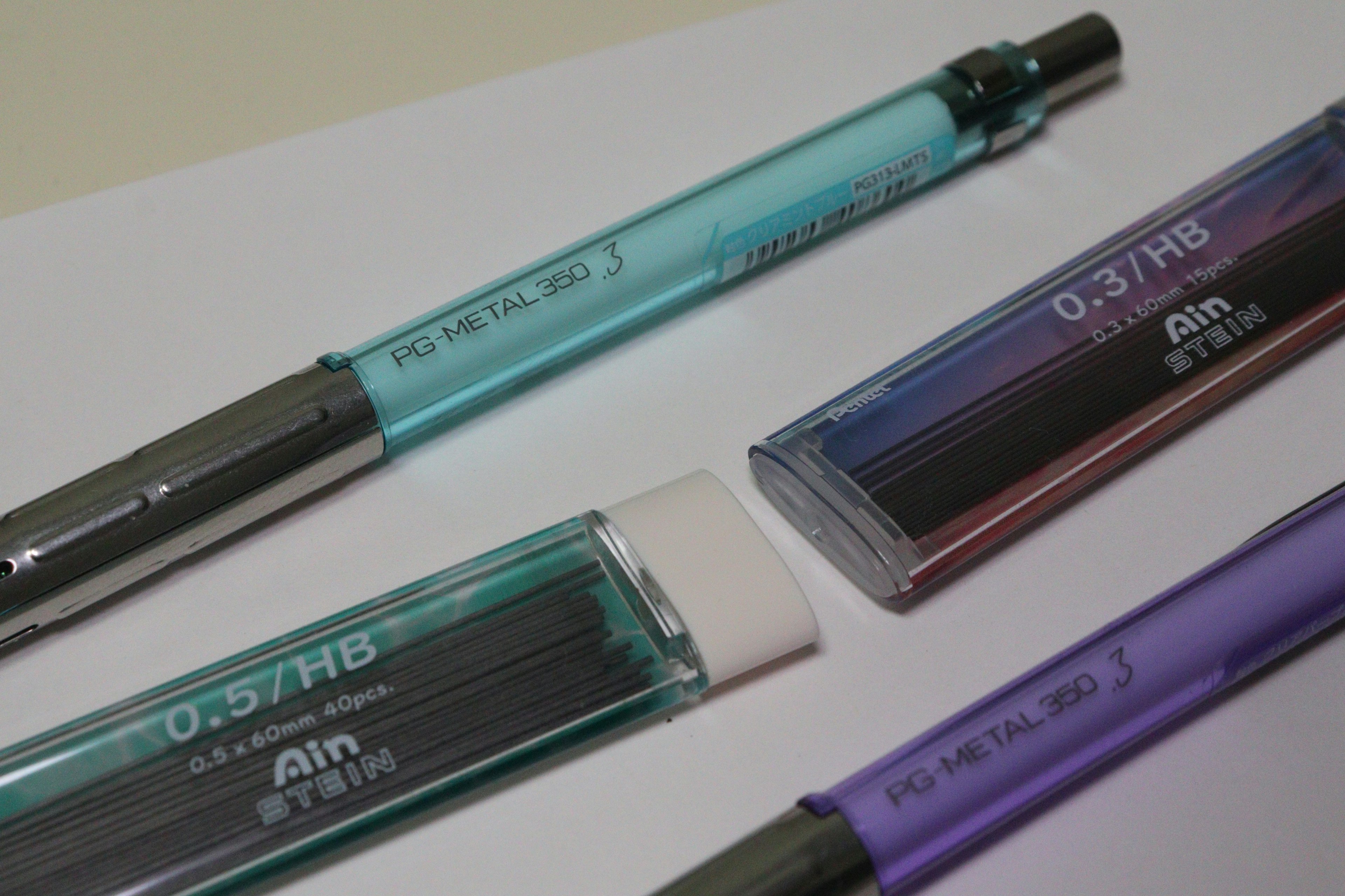 Quatre stylos colorés en bleu canard et violet avec des étuis transparents