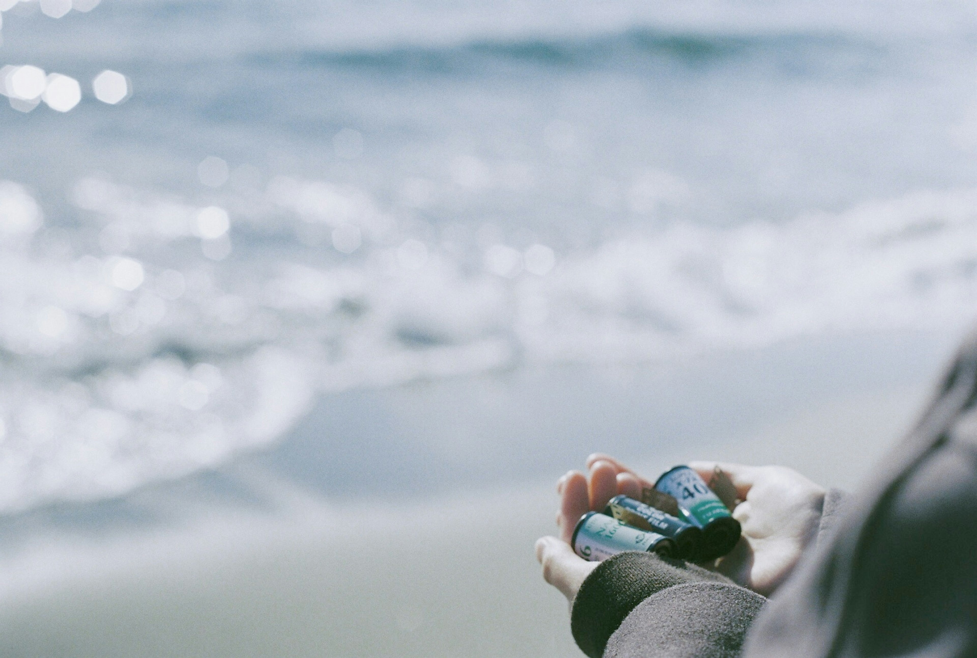 Mano che tiene una piccola conchiglia blu sulla spiaggia