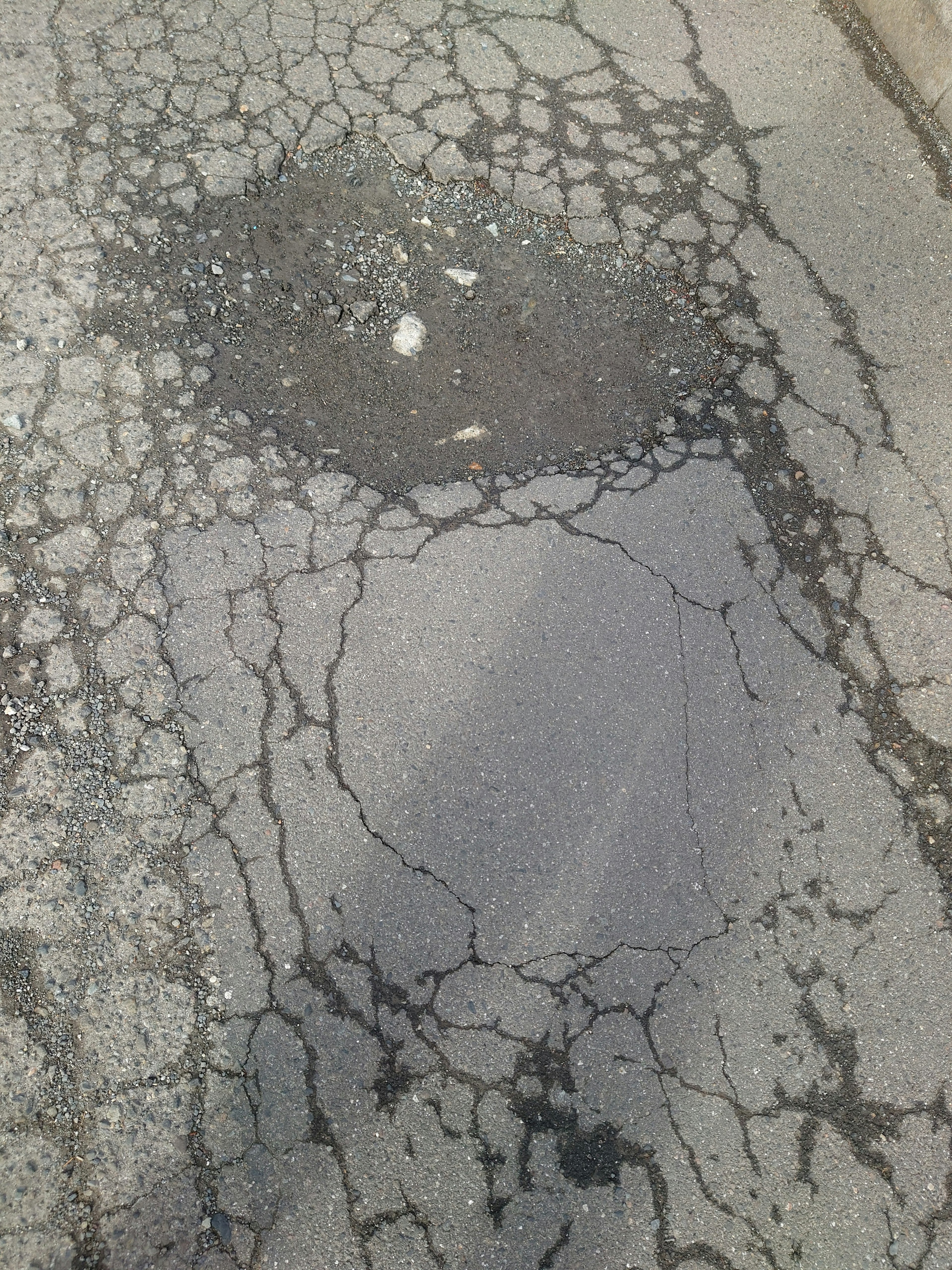 Large pothole on cracked asphalt road