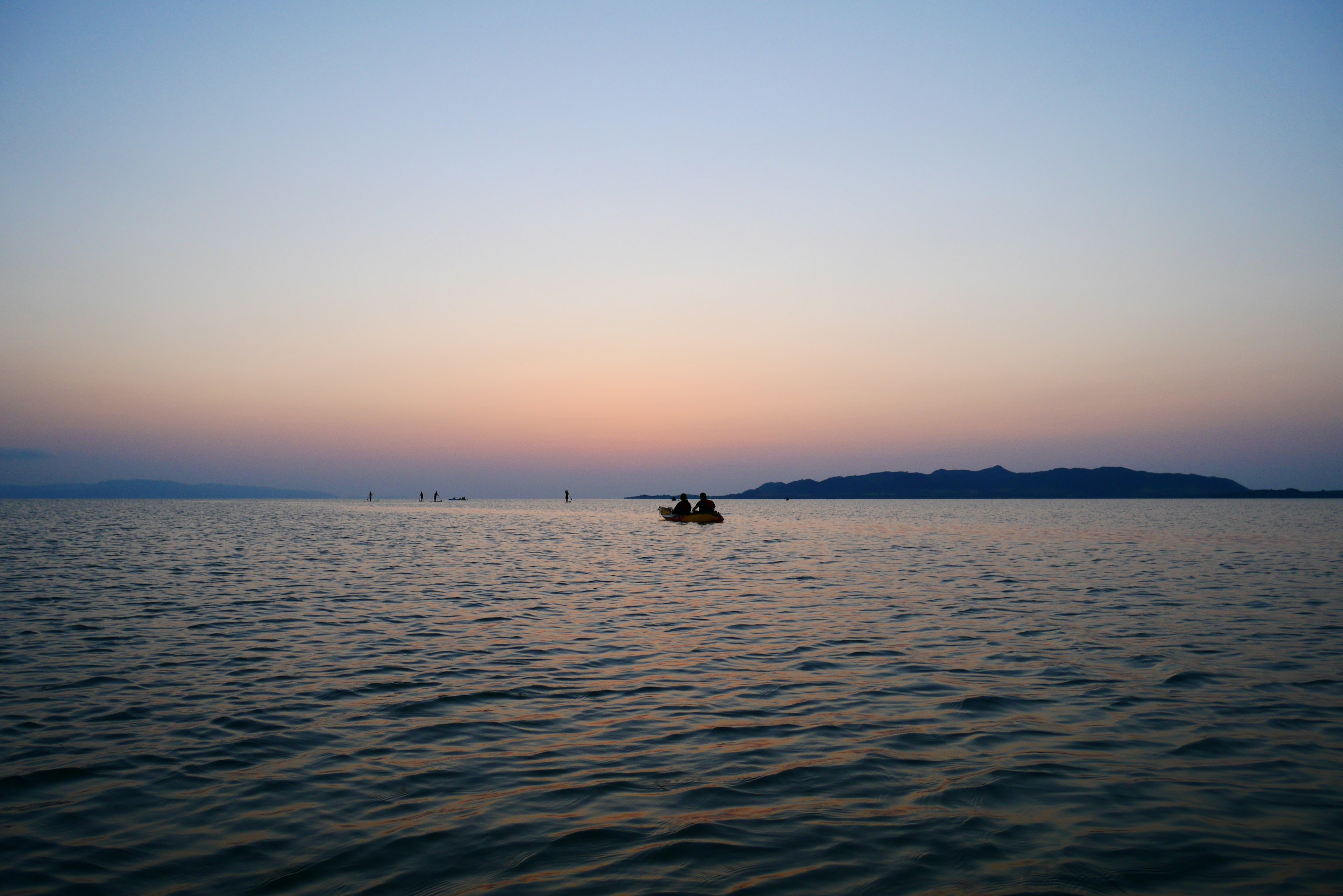 Un petit bateau flottant sur une eau calme sous un ciel pastel