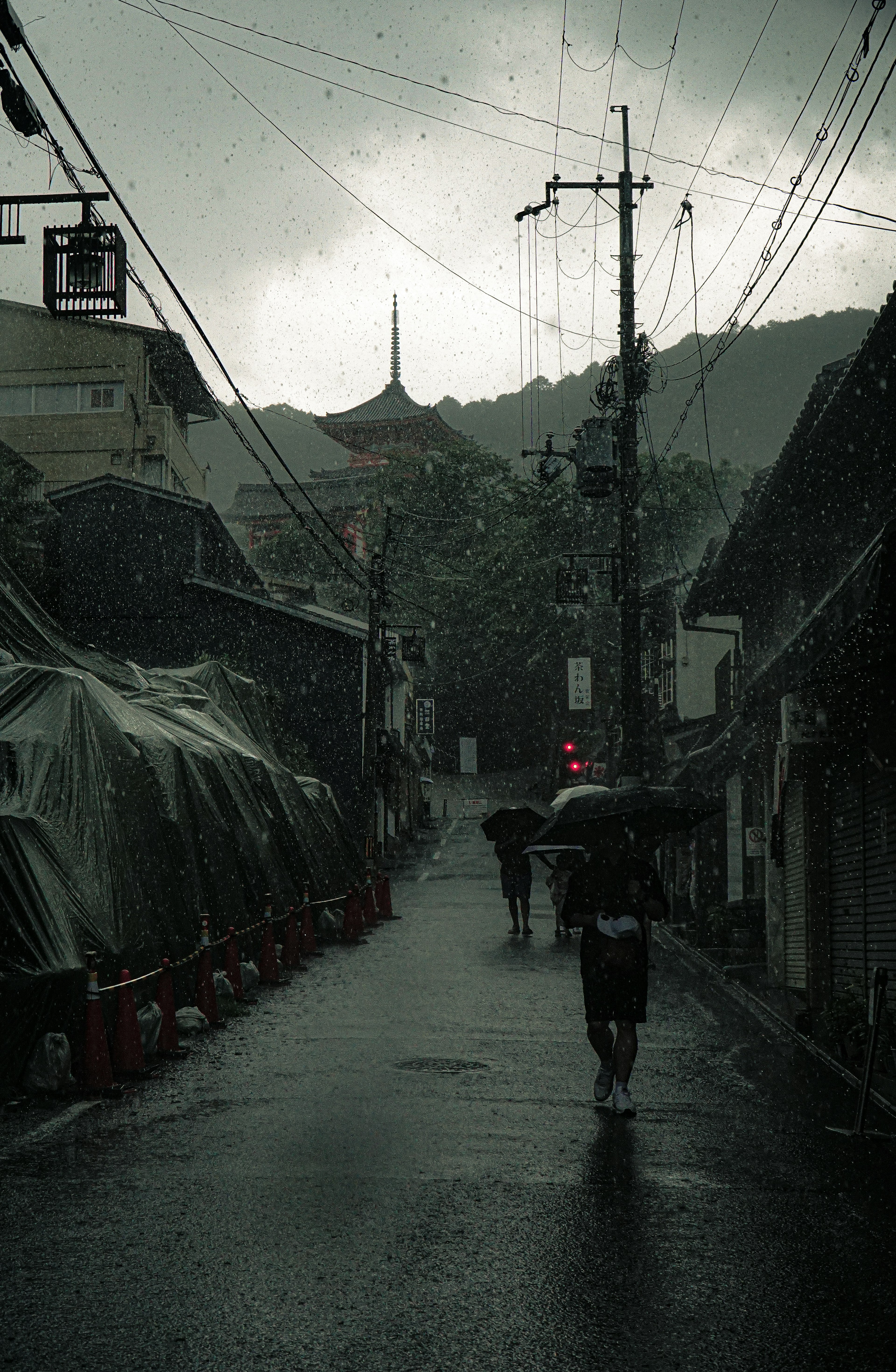 雨の中を歩く人々と暗い空の街並み