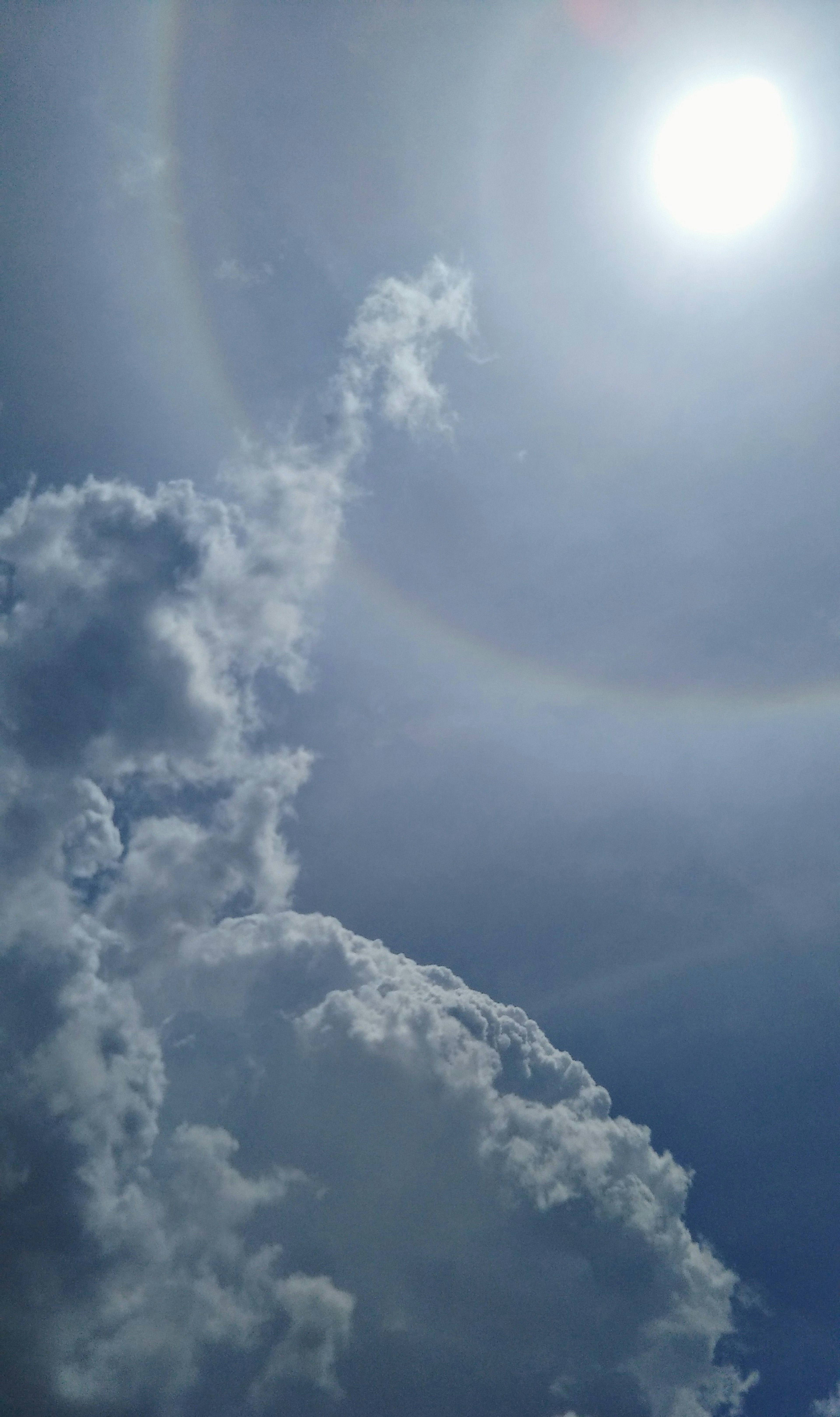 Nubes blancas en un cielo azul con un halo alrededor del sol