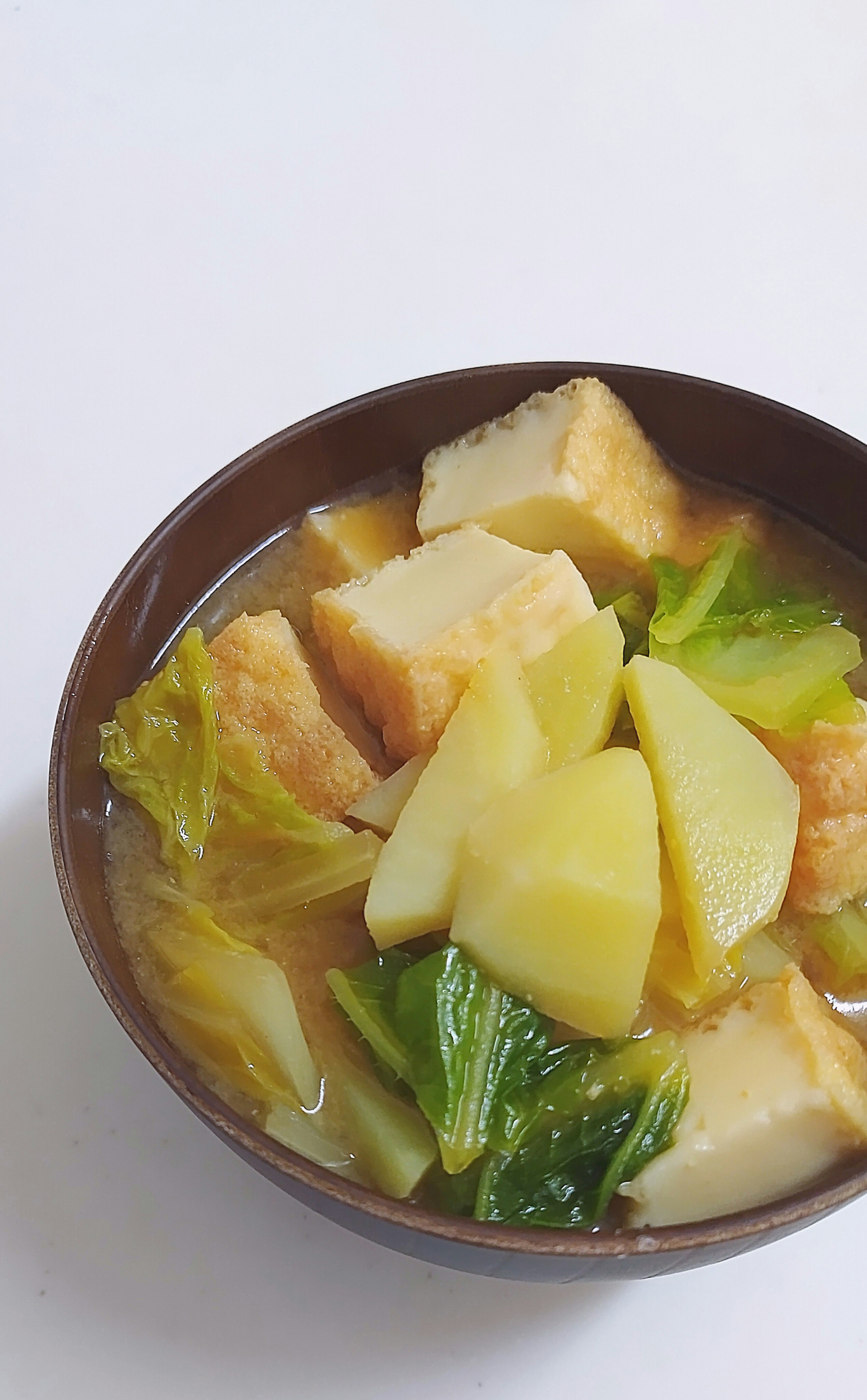 Bowl of tofu and vegetable soup with potatoes and greens