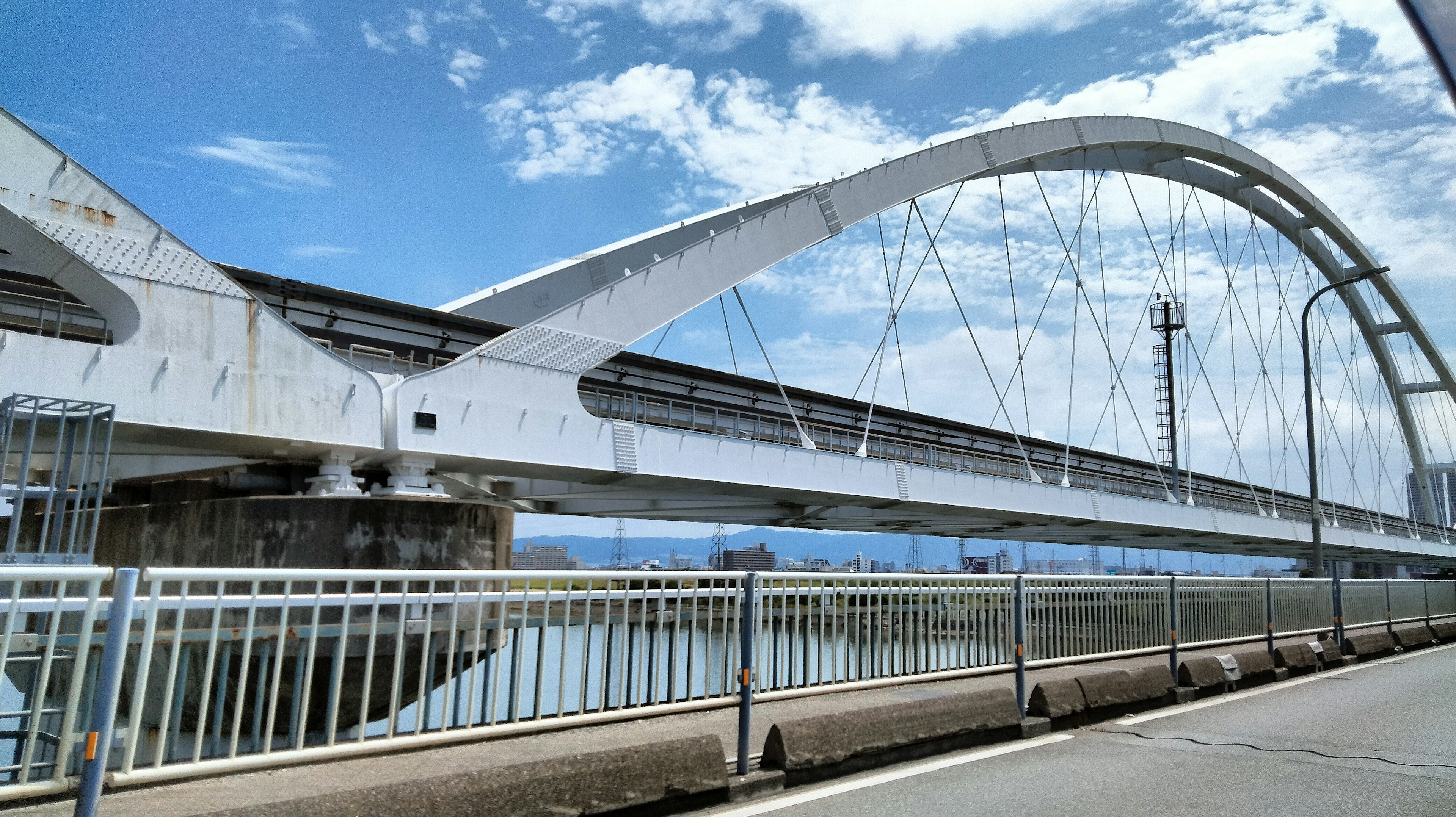 A white arch bridge spans a river under a blue sky