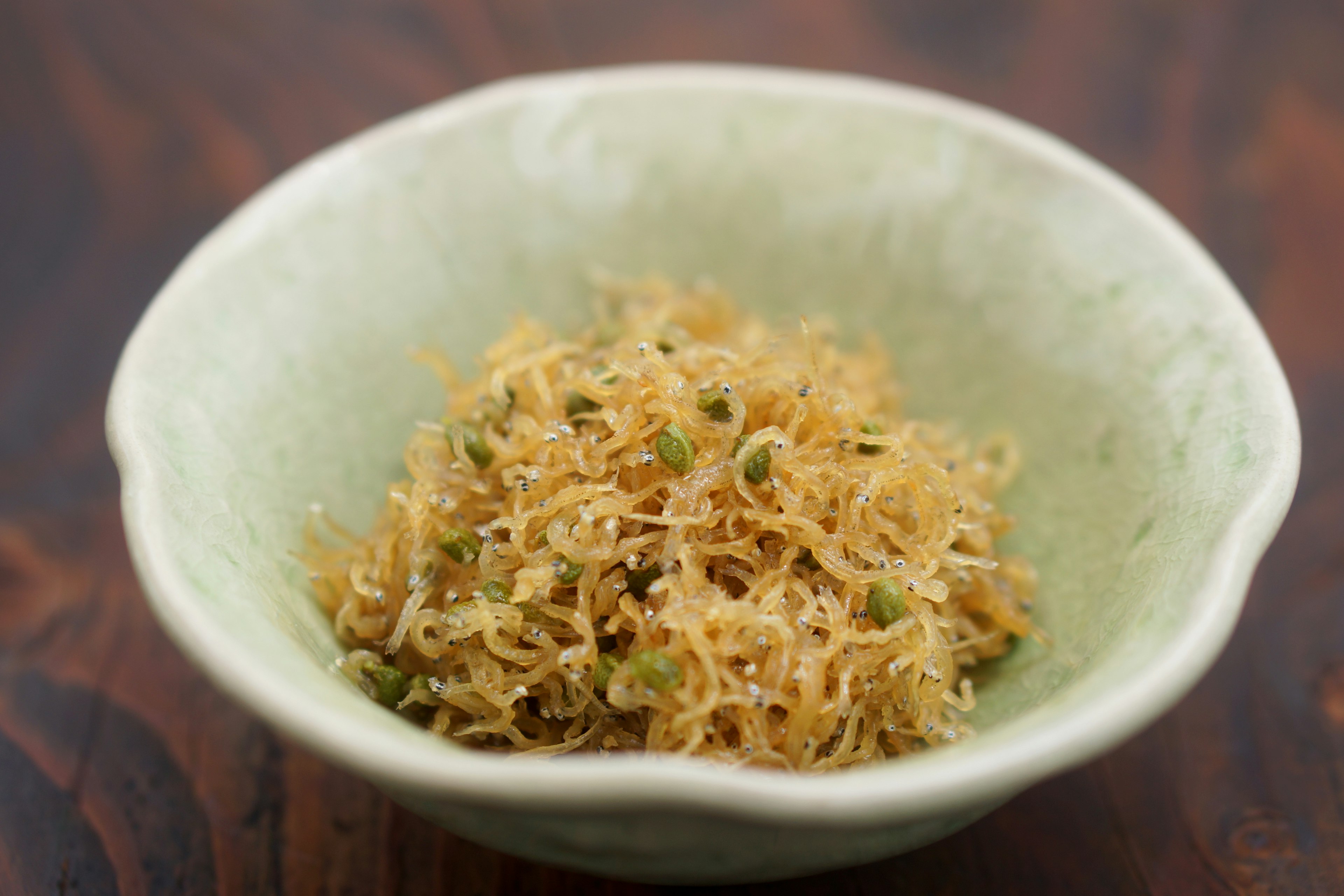 A small green bowl filled with finely shredded dried fish dish