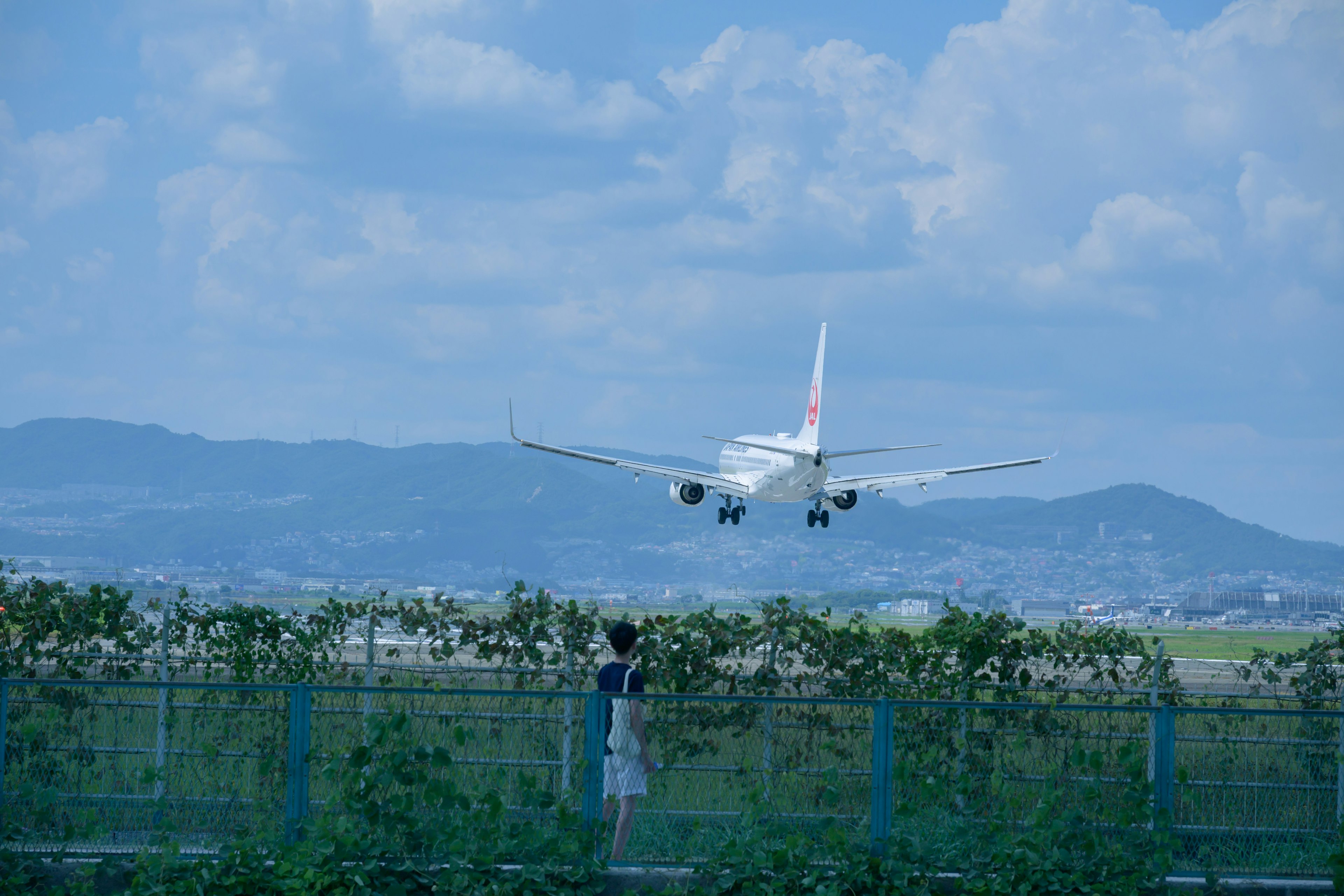 Bambino che osserva un aereo atterrare sotto un cielo blu