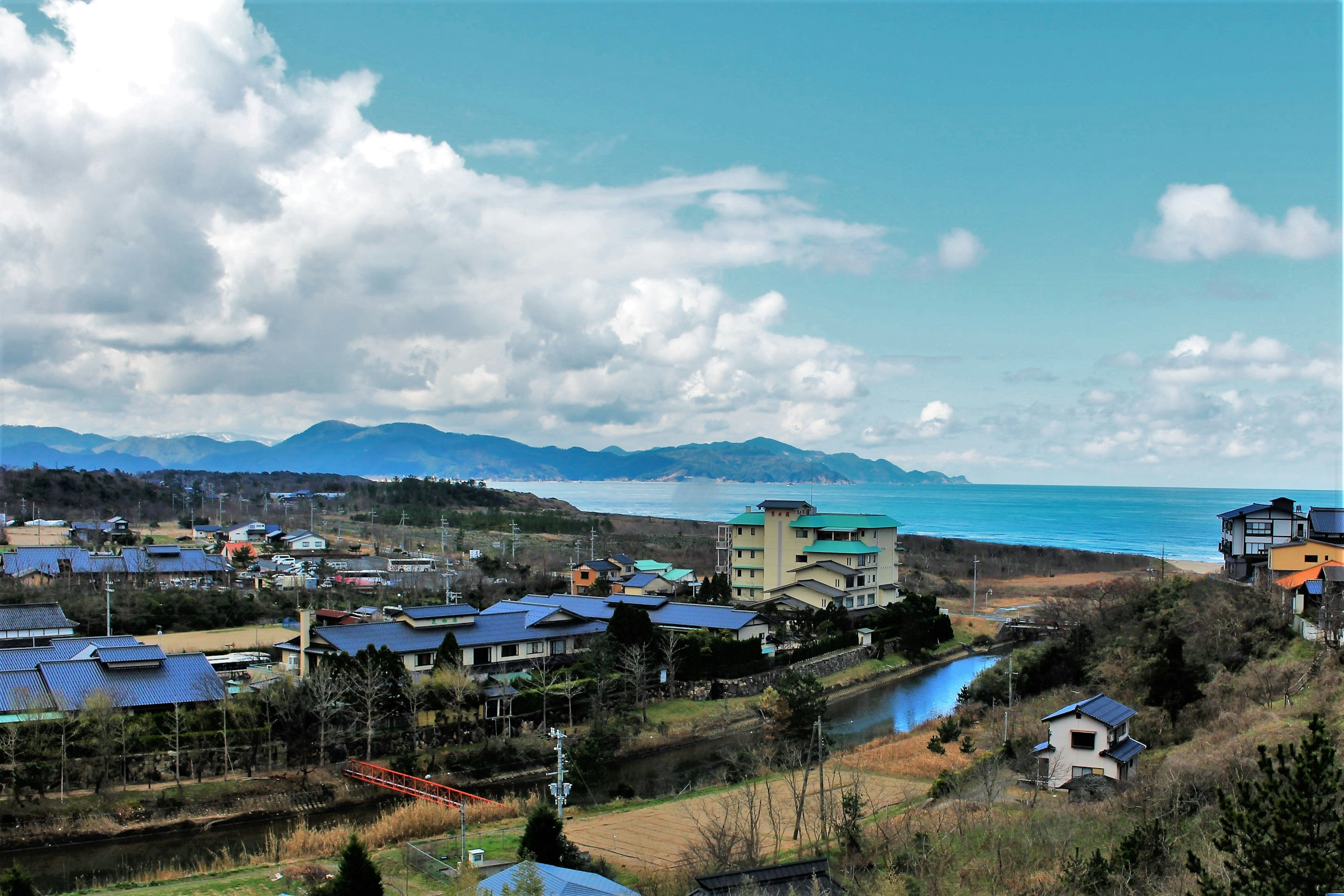 海岸風景，藍色屋頂的房屋俯瞰大海和群山