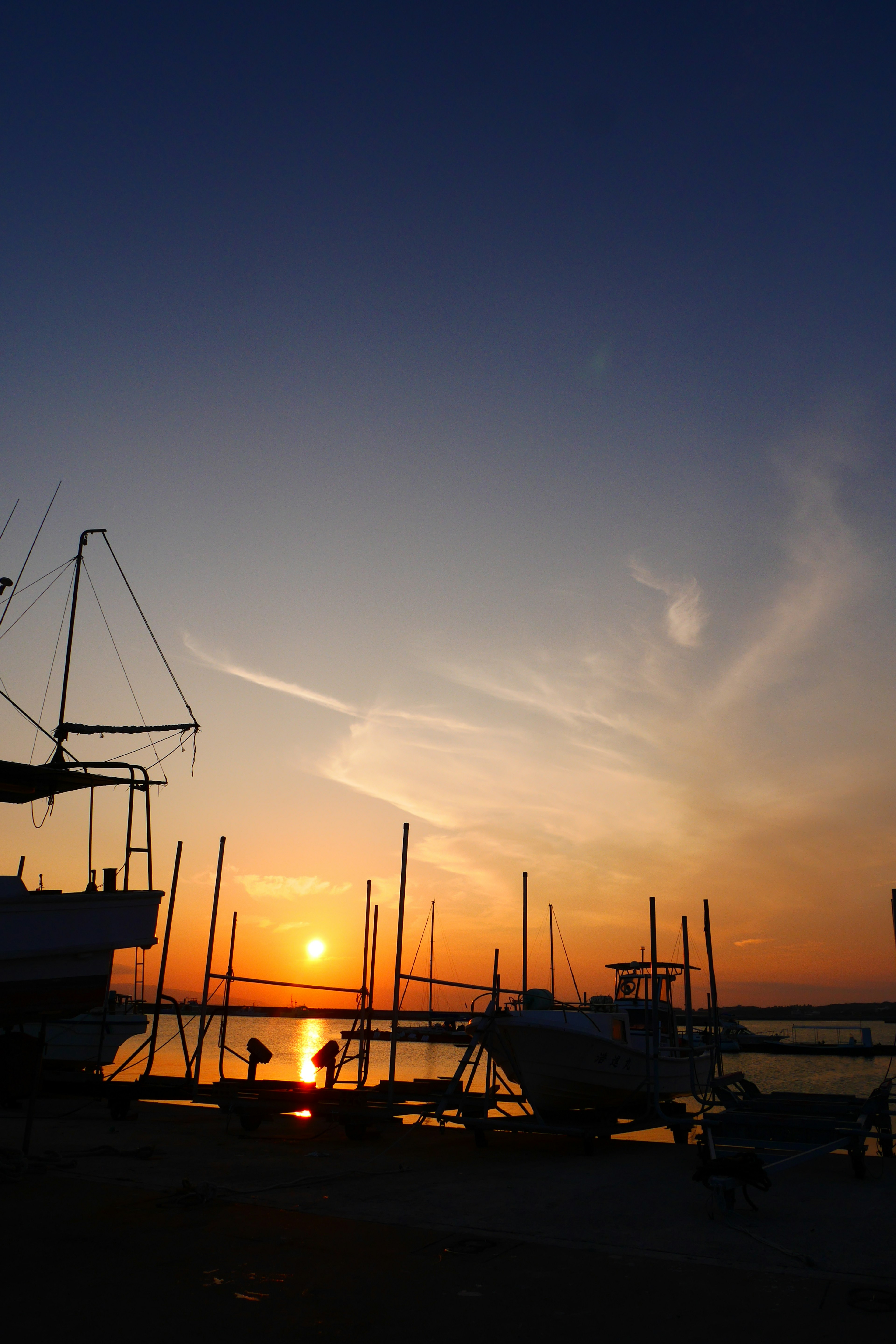 Silhouette von Booten vor einem lebhaften Sonnenuntergang an der Küste