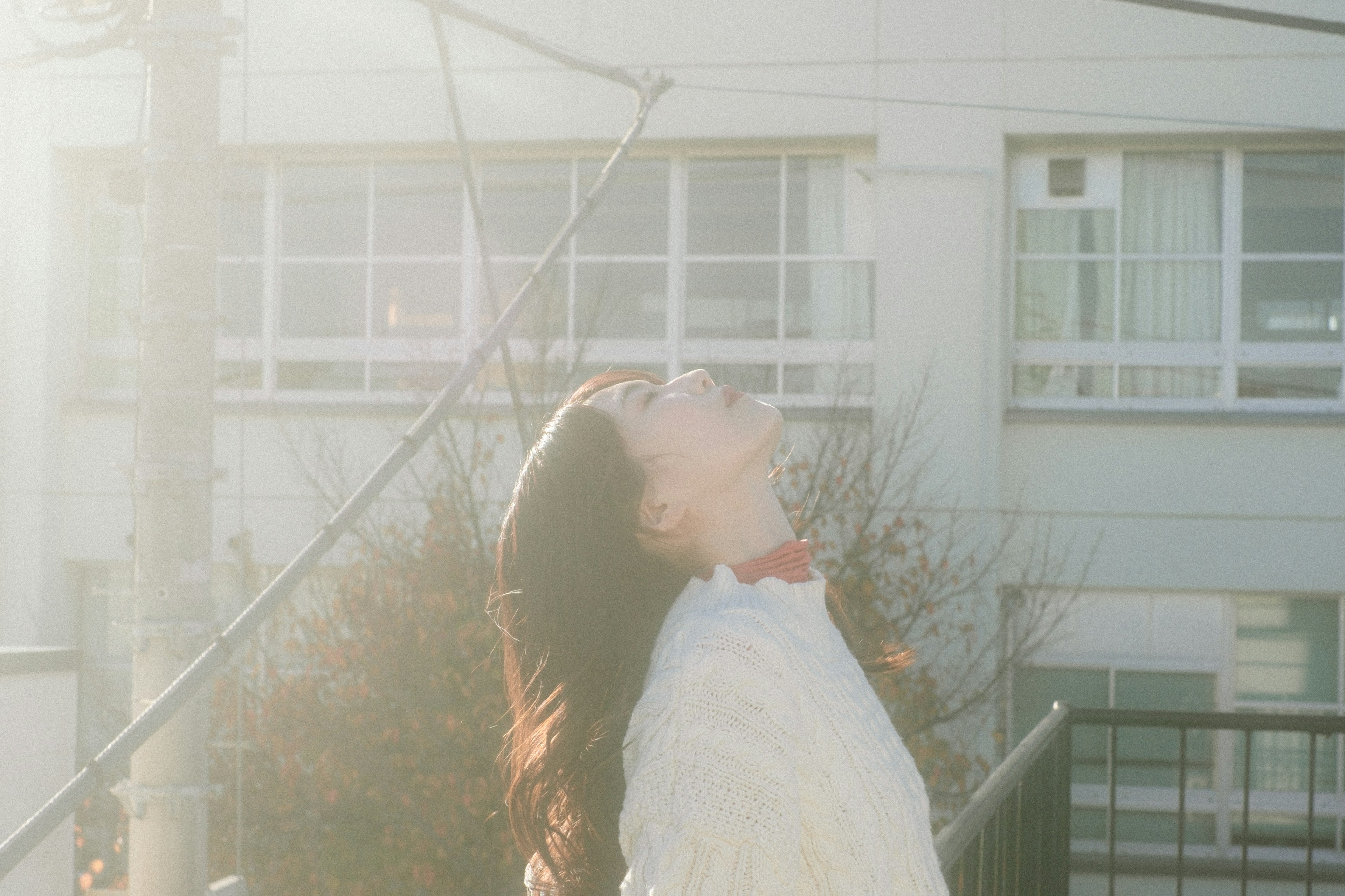 女性が日の出の光の中で空を見上げている