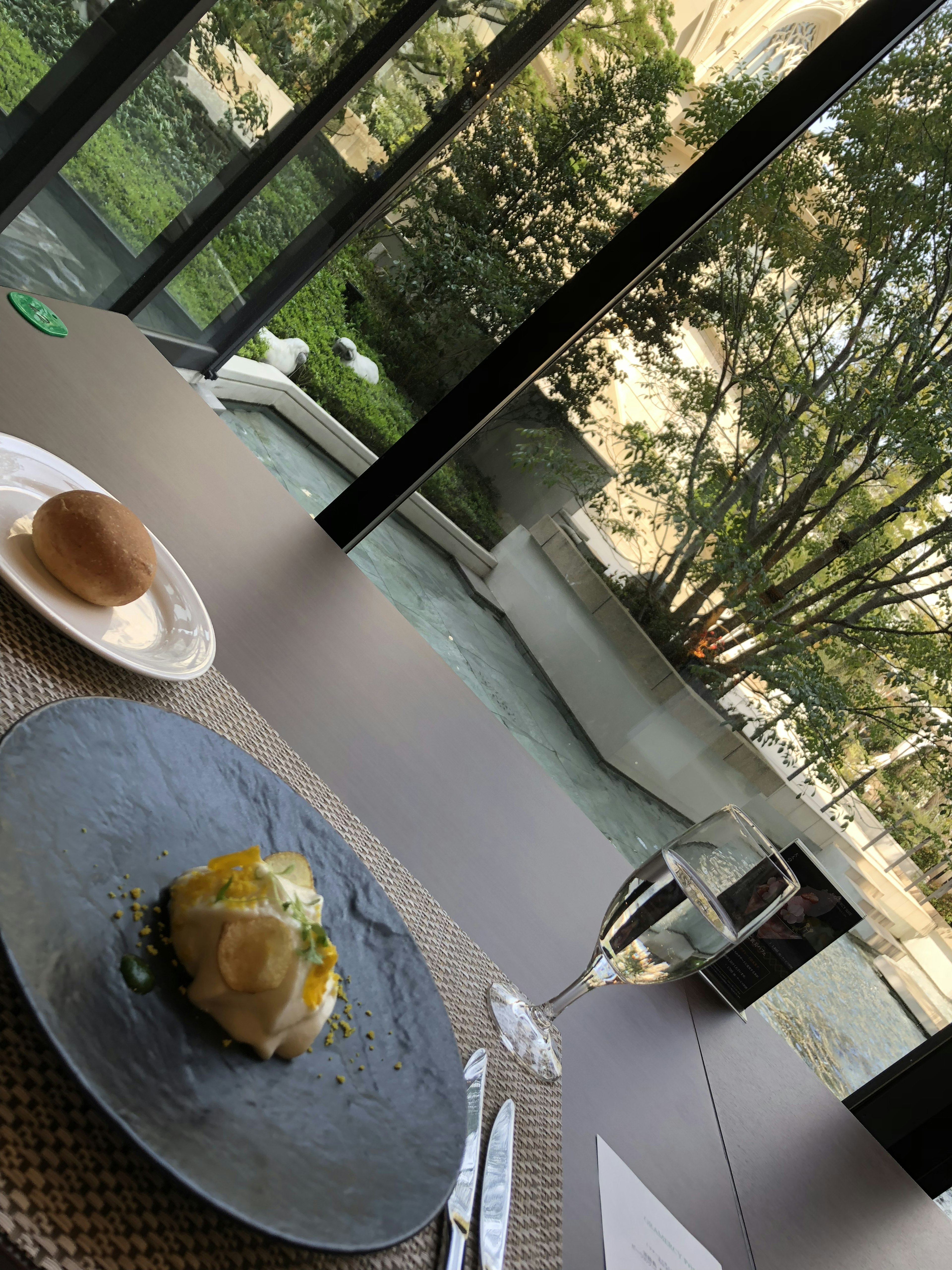 Mesa con plato gourmet y pan con vista a un hermoso jardín