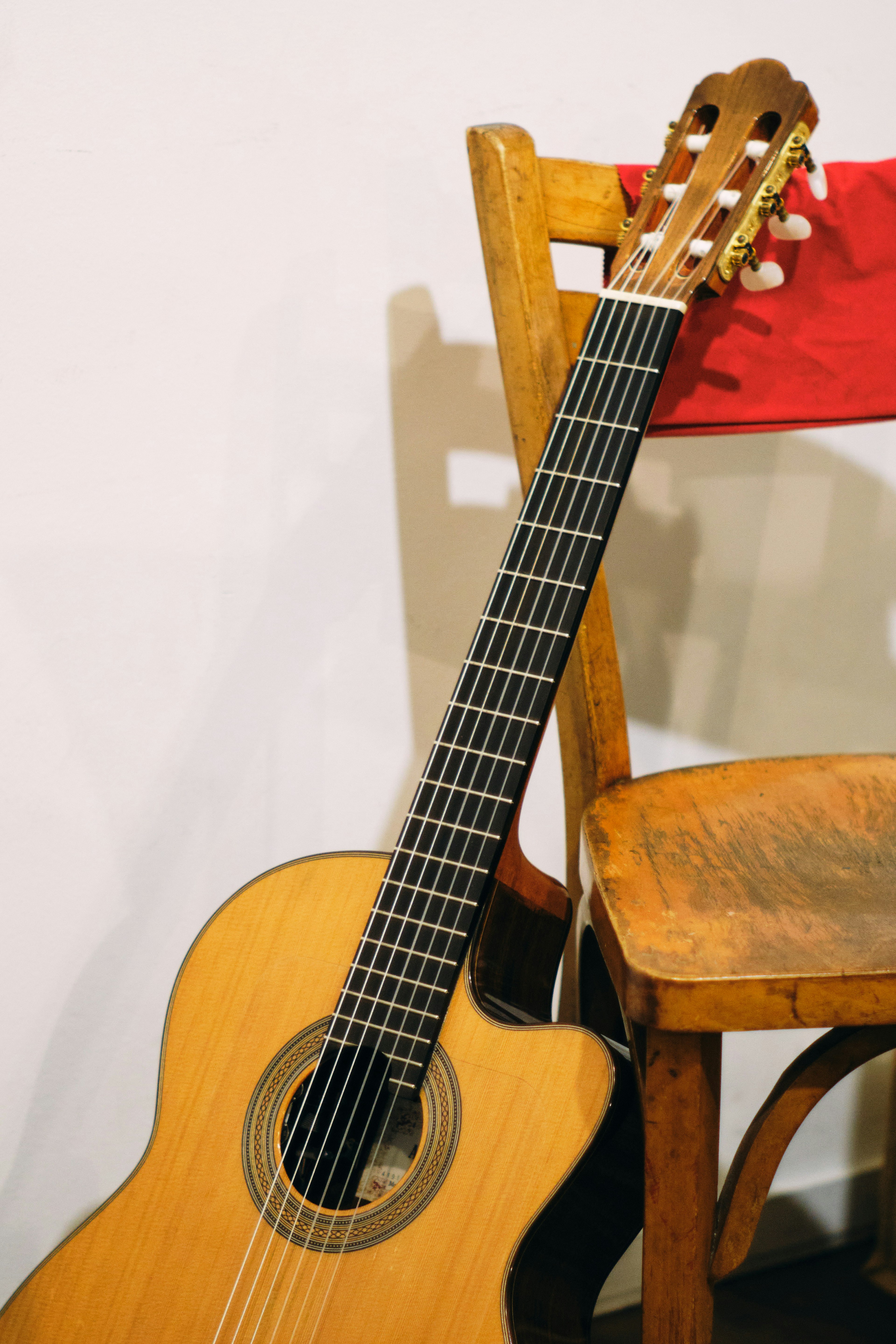 An acoustic guitar resting against a wooden chair