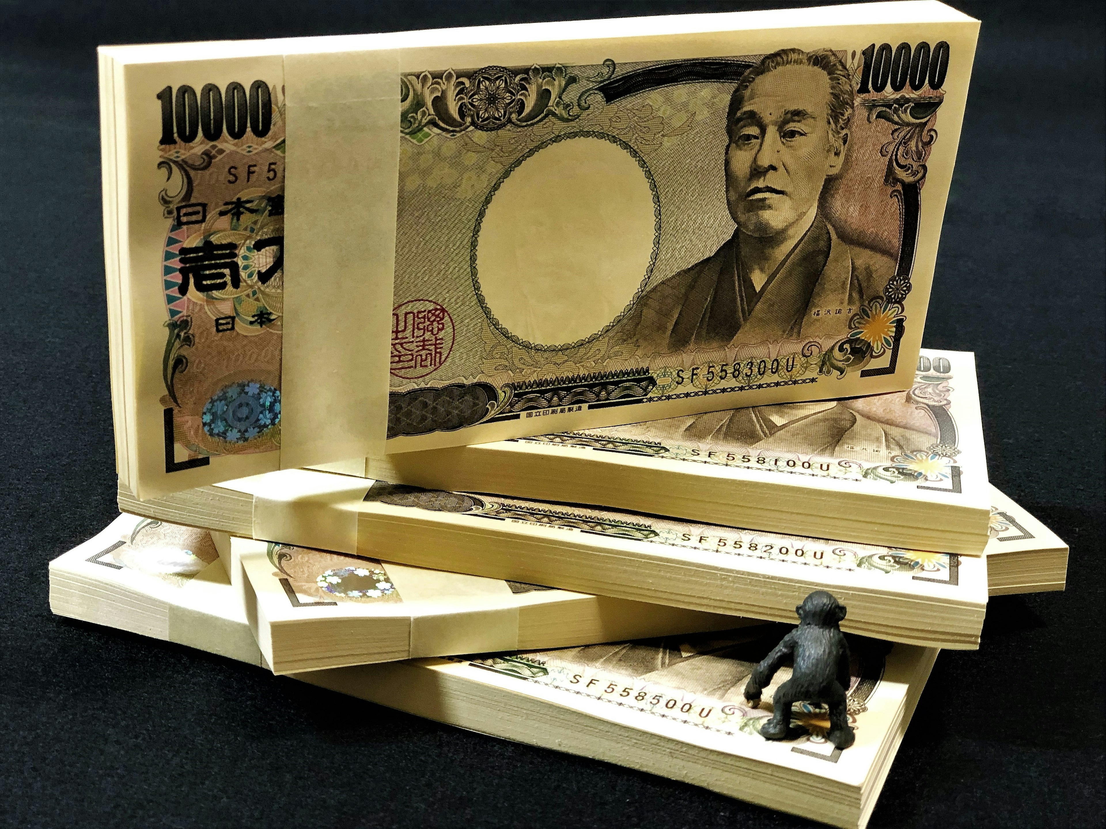 Stack of Japanese 10000 yen bills with a small figurine