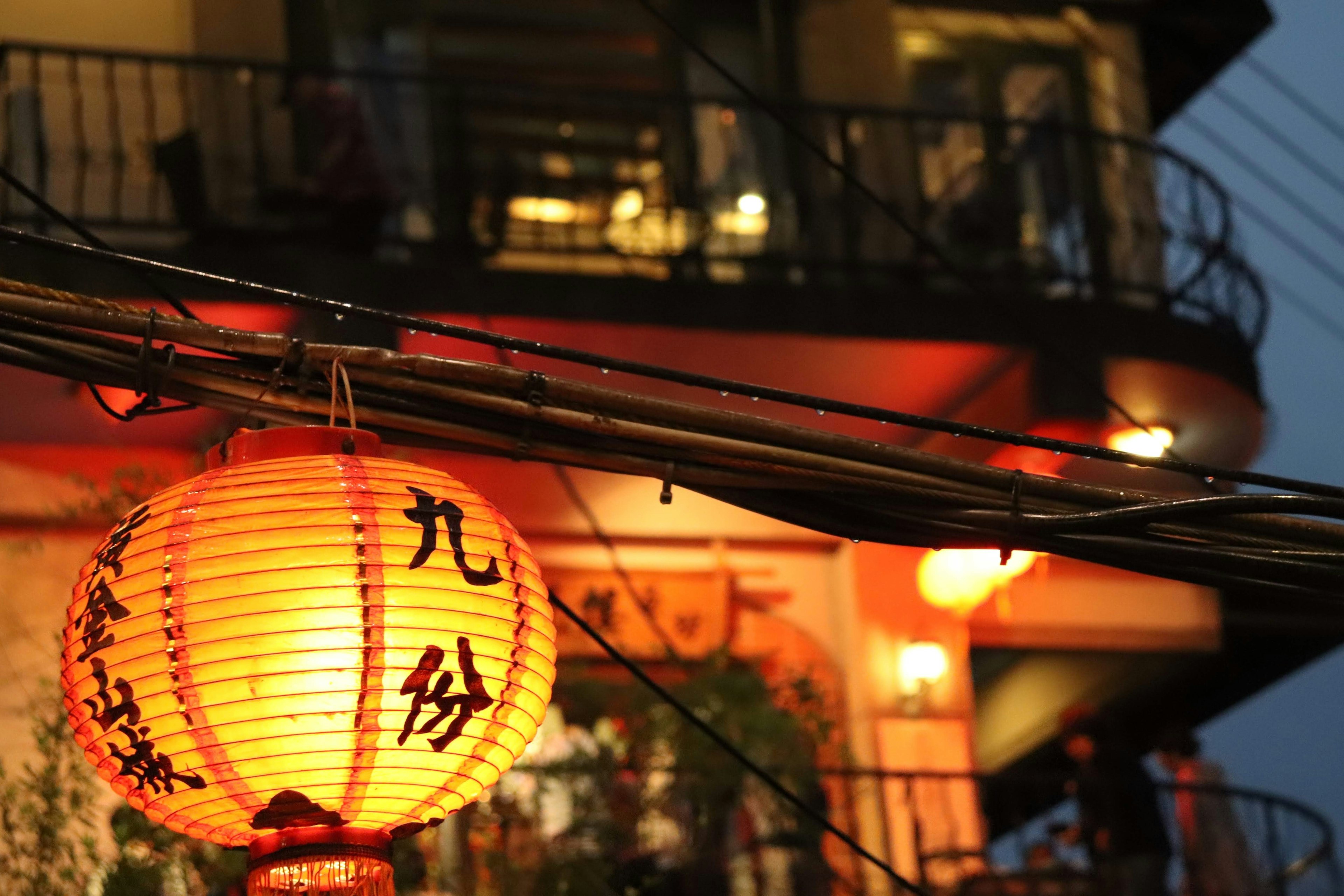 Red lantern illuminated at night with a building featuring a balcony