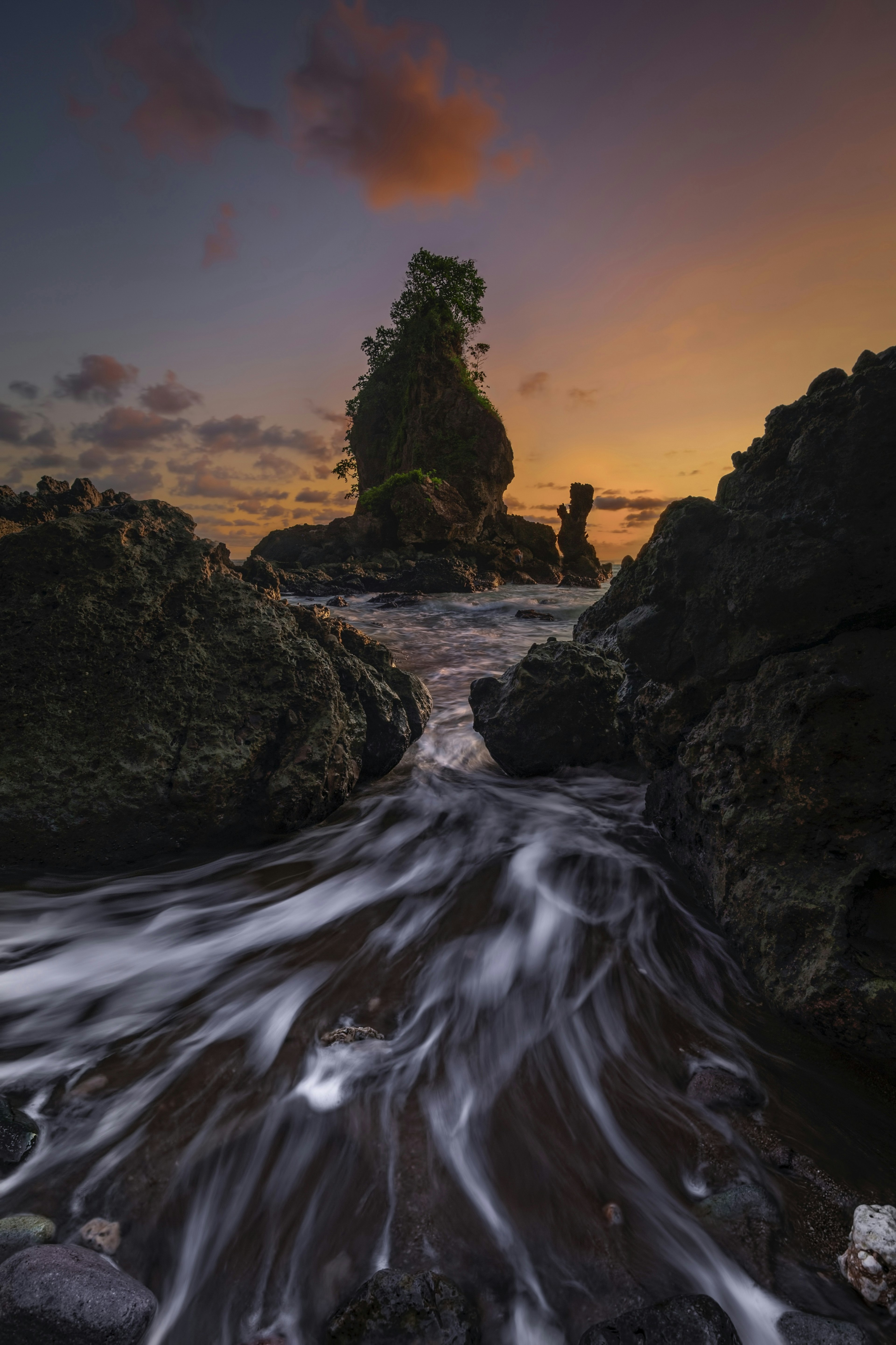 Pemandangan air mengalir dan batuan saat matahari terbenam