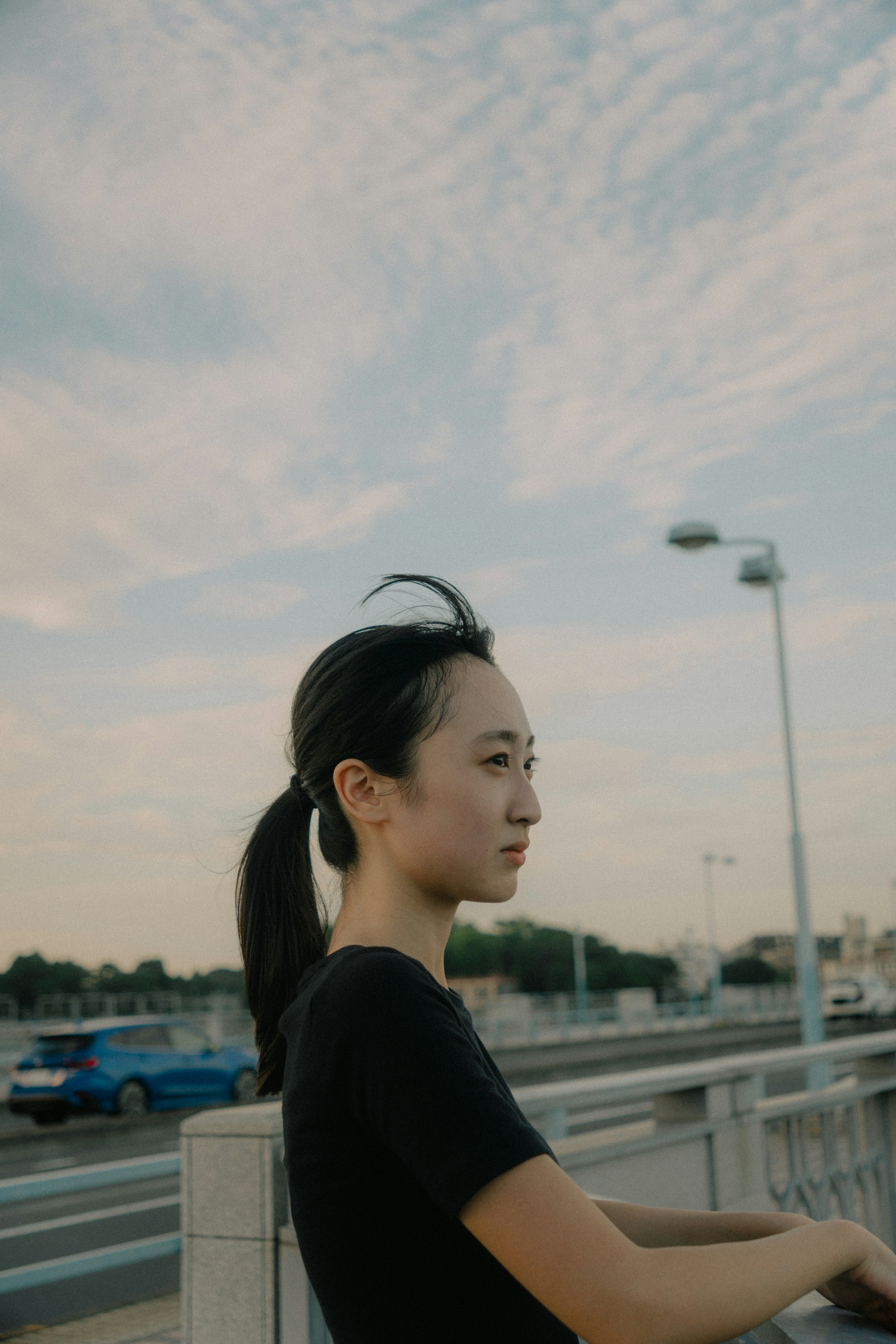 Profil d'une femme pensant sur un pont avec un ciel bleu