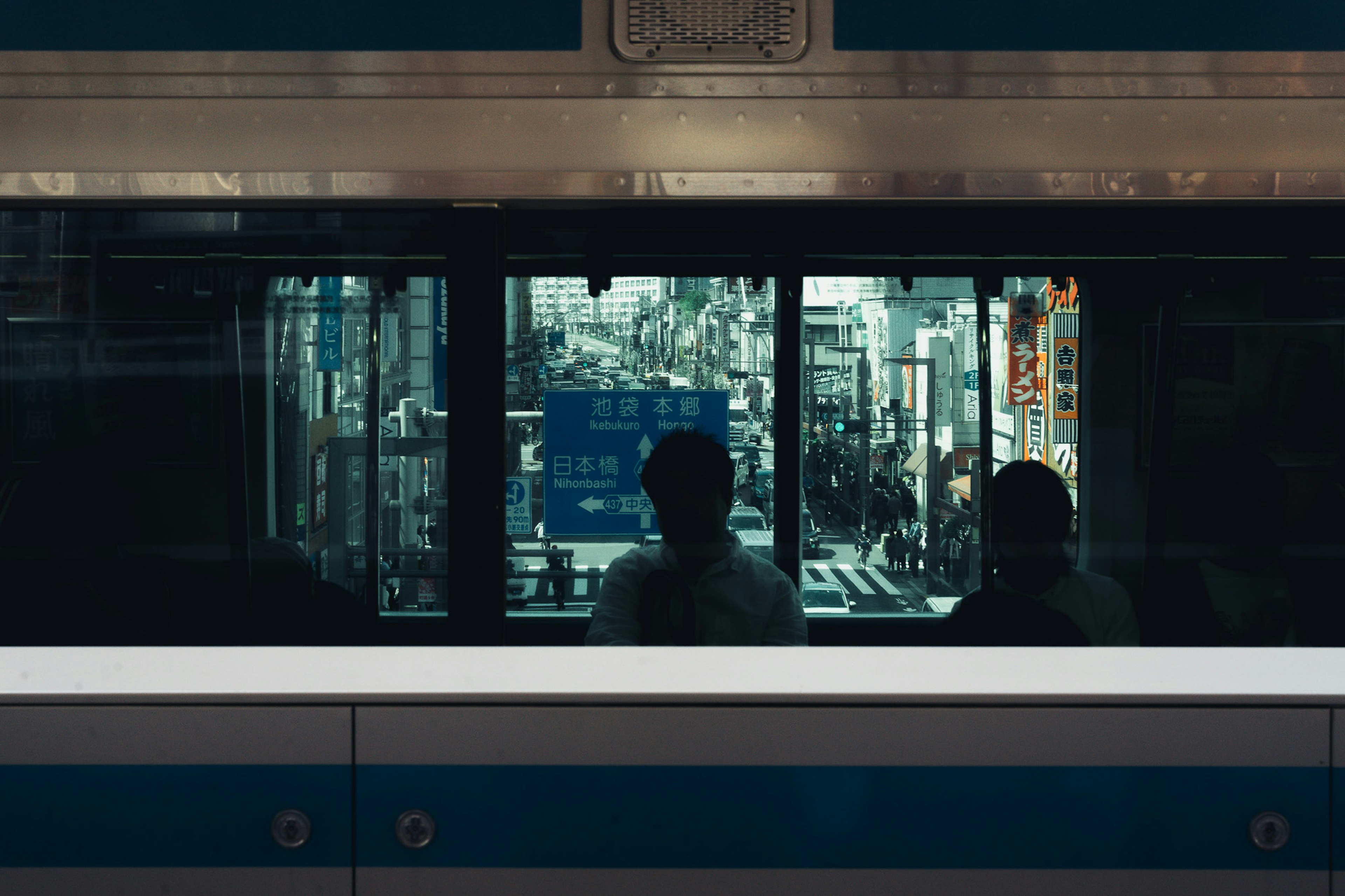 電車の窓越しに見える都会の風景と二人の乗客