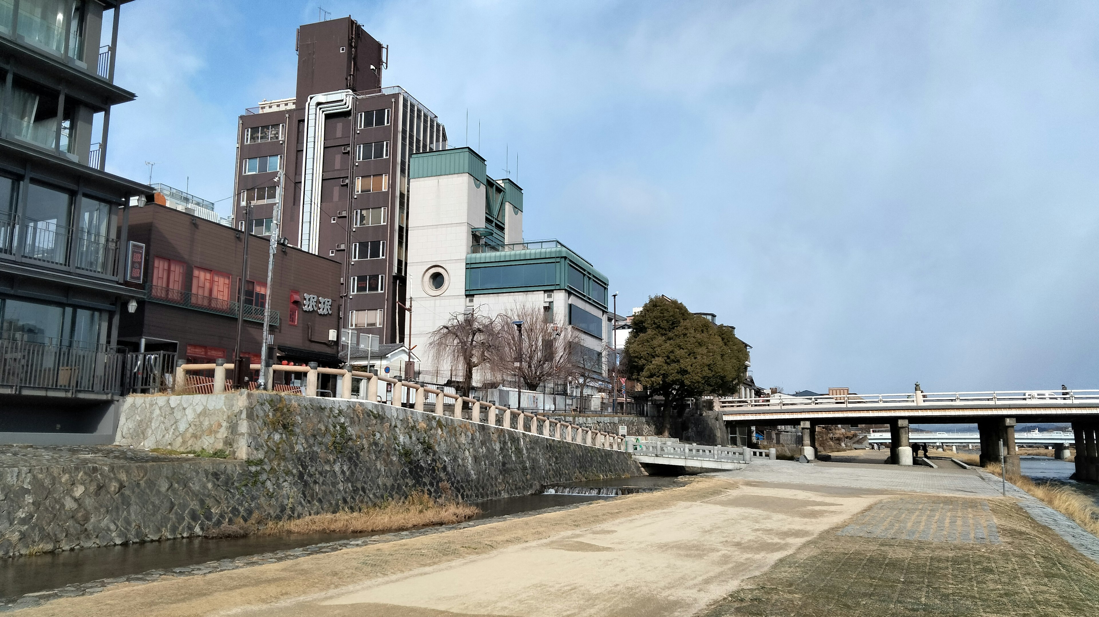 Modern buildings near a riverbank with a clear sky