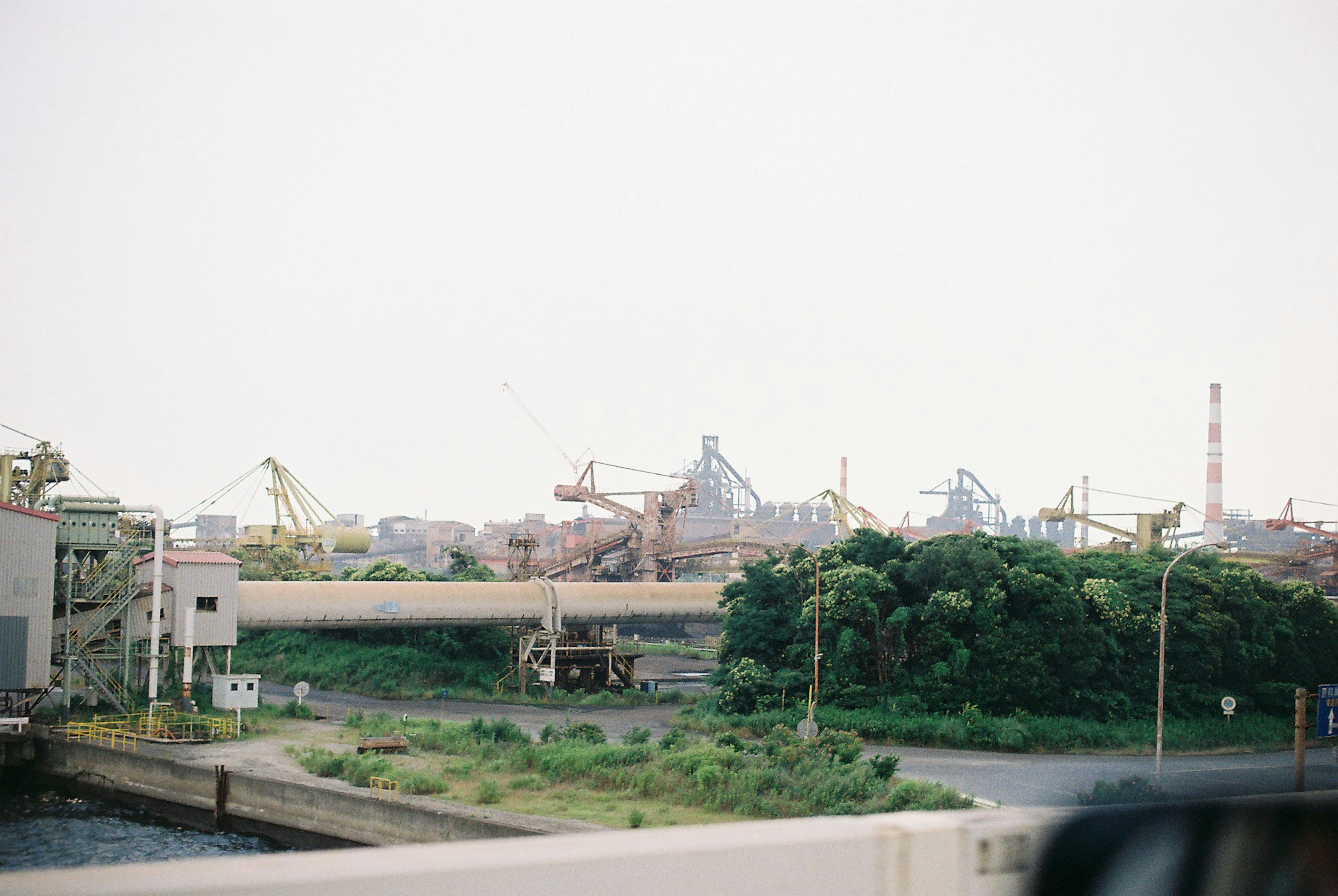 View of cranes in a port with green vegetation