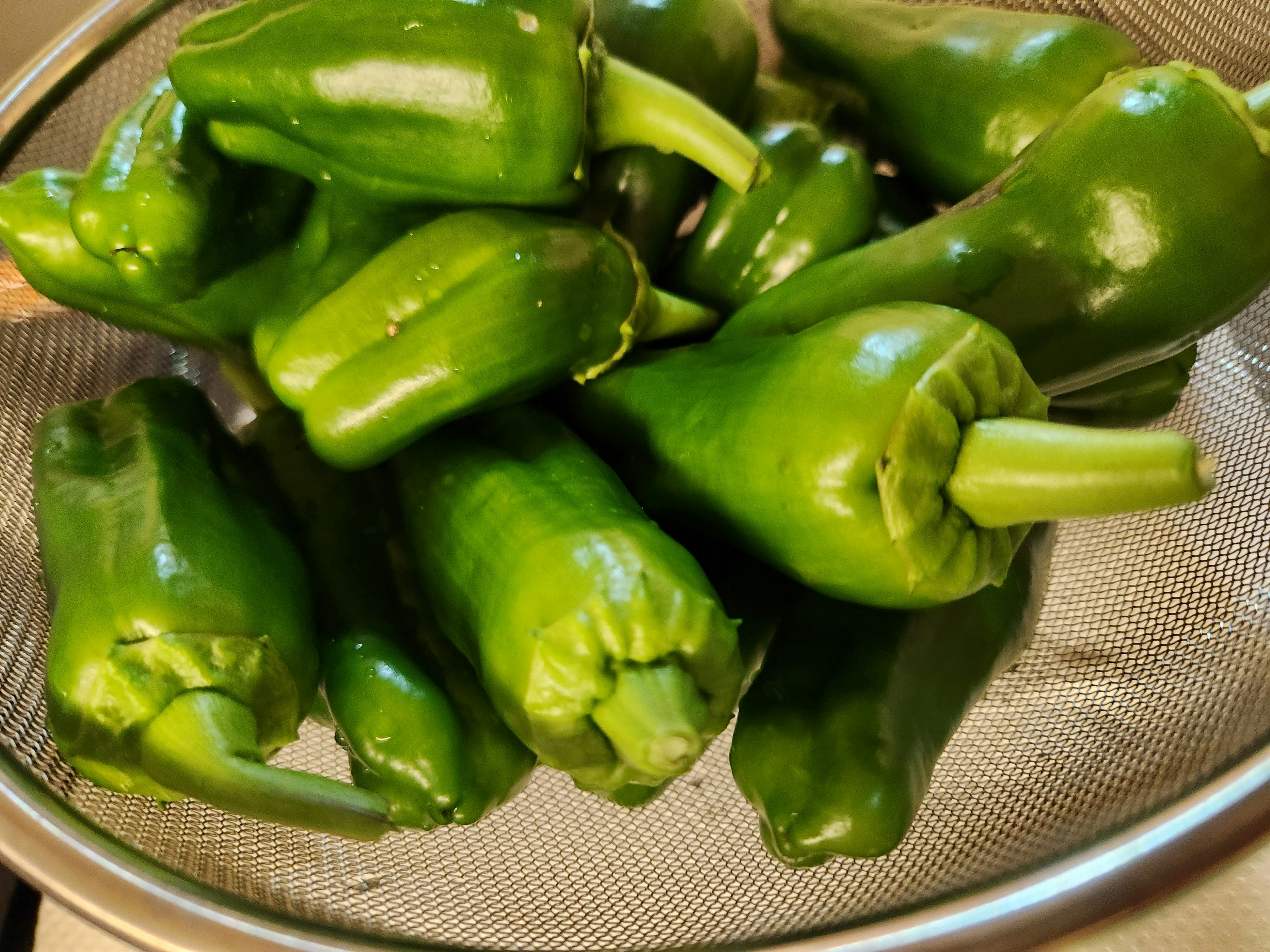 Fresh green peppers piled in a strainer