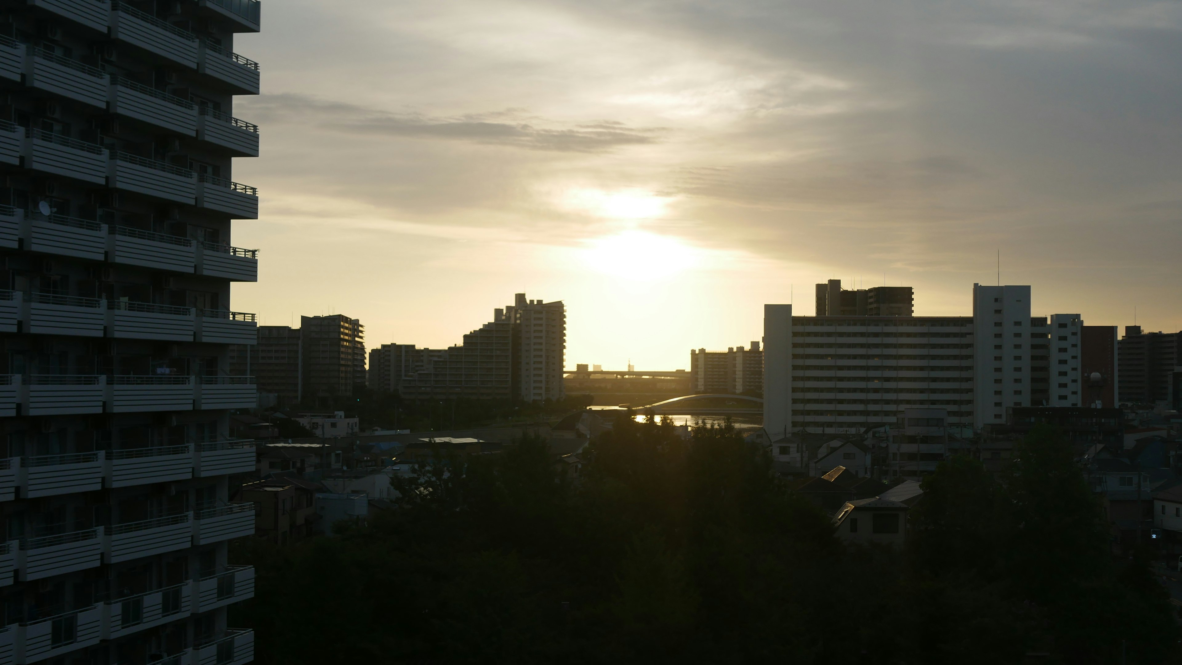 Cityscape at sunset featuring tall buildings and a river