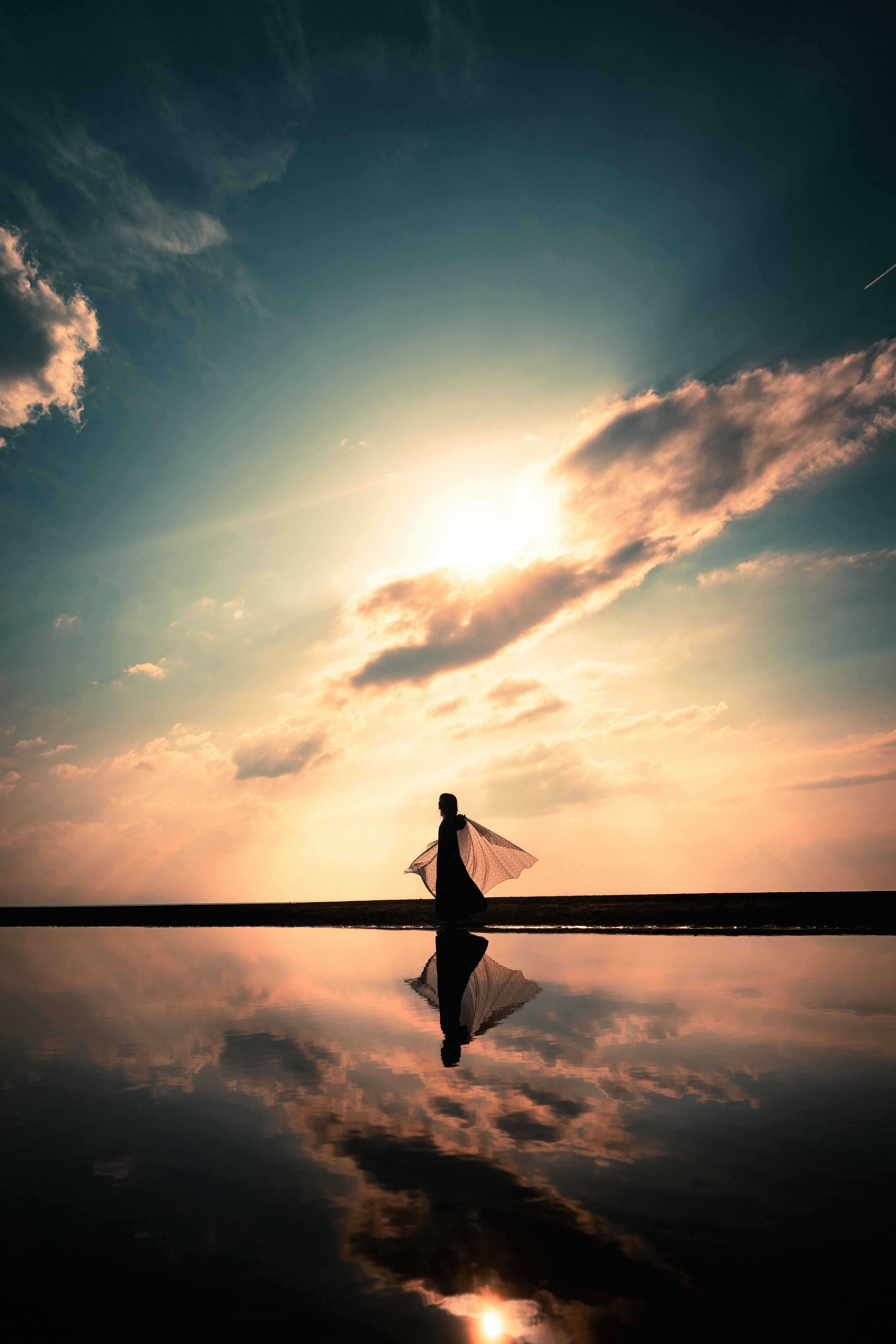 Silhouette di una donna contro un bellissimo tramonto e riflesso sull'acqua