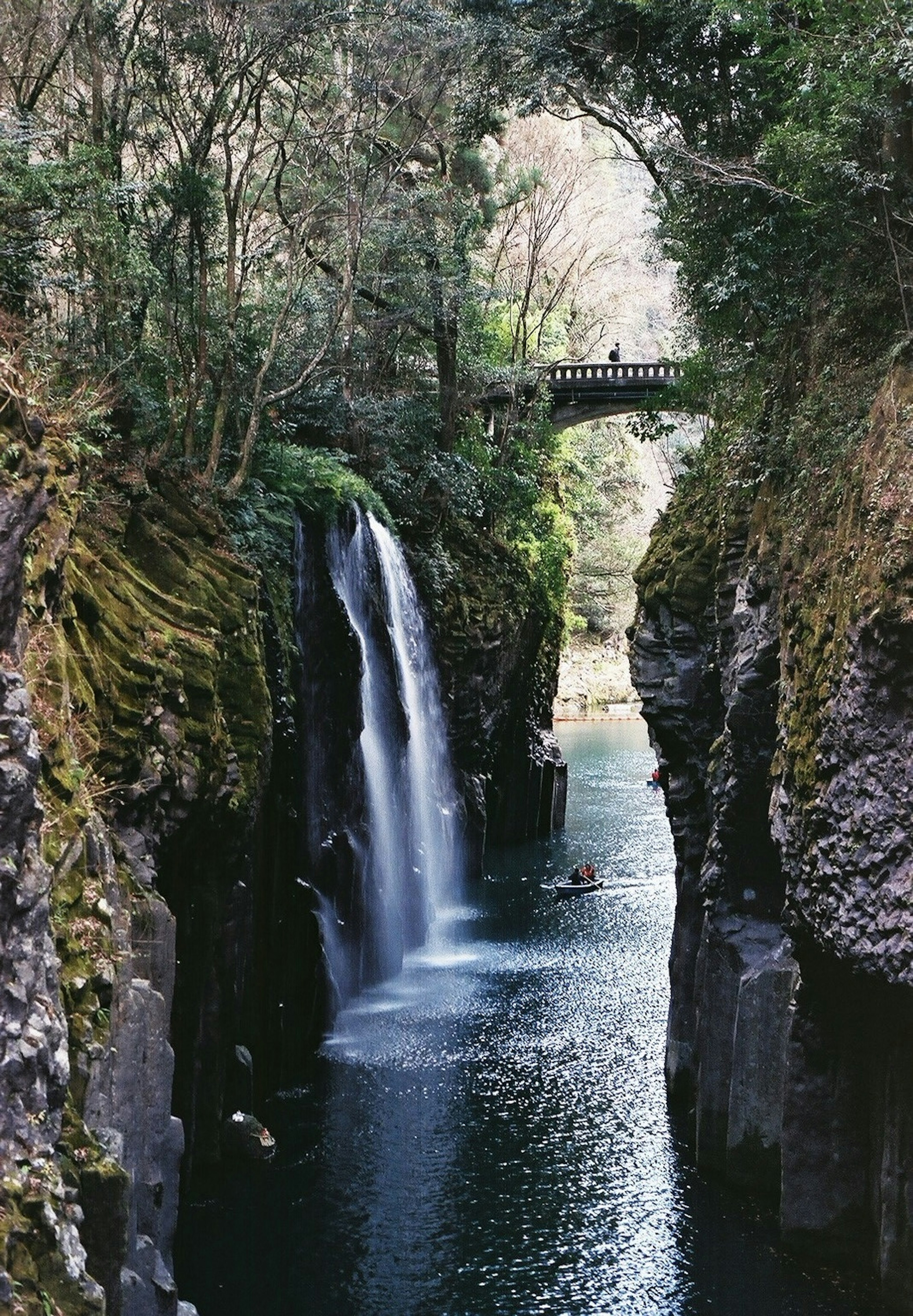 Vista escénica de un cañón con una cascada y un puente