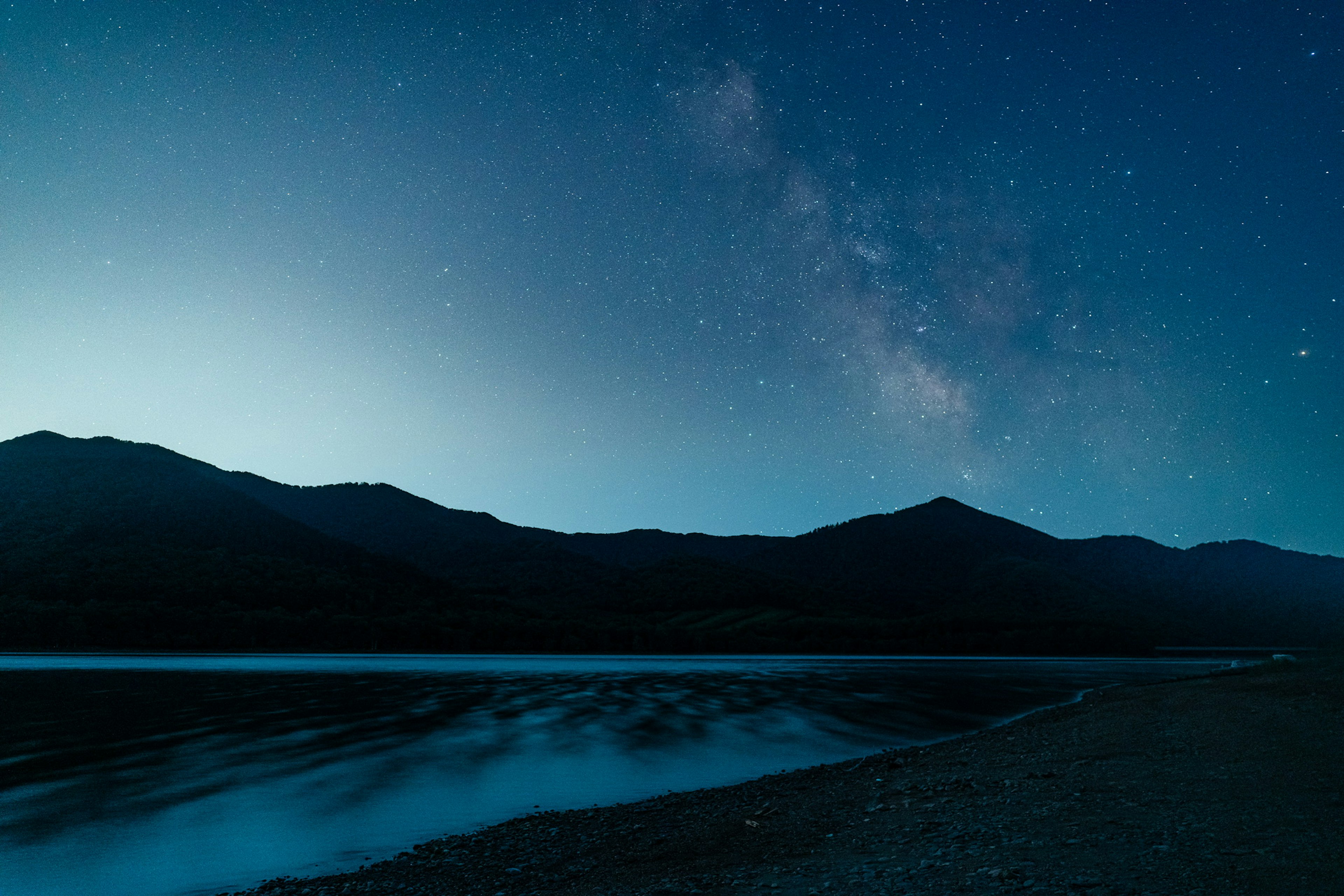 夜空中可见银河的宁静湖泊场景和黑暗的山脉