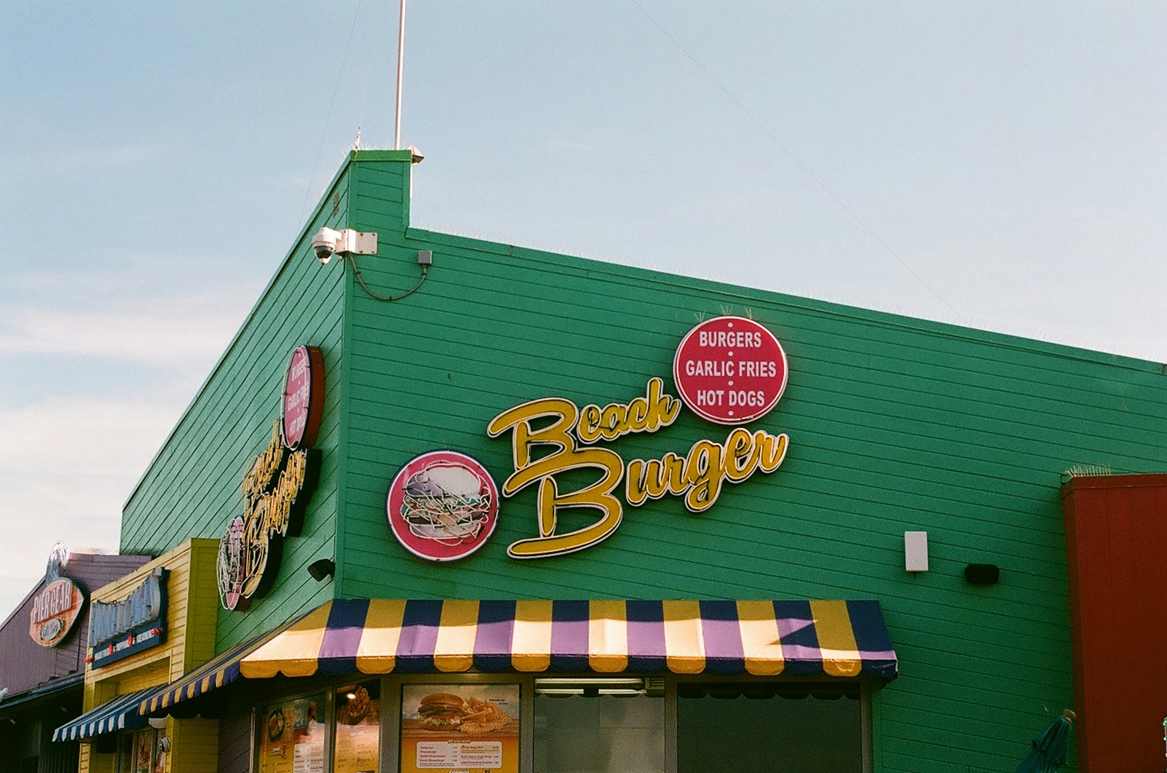 色彩鲜艳的Beach Burger外观，绿色墙壁和条纹遮阳篷