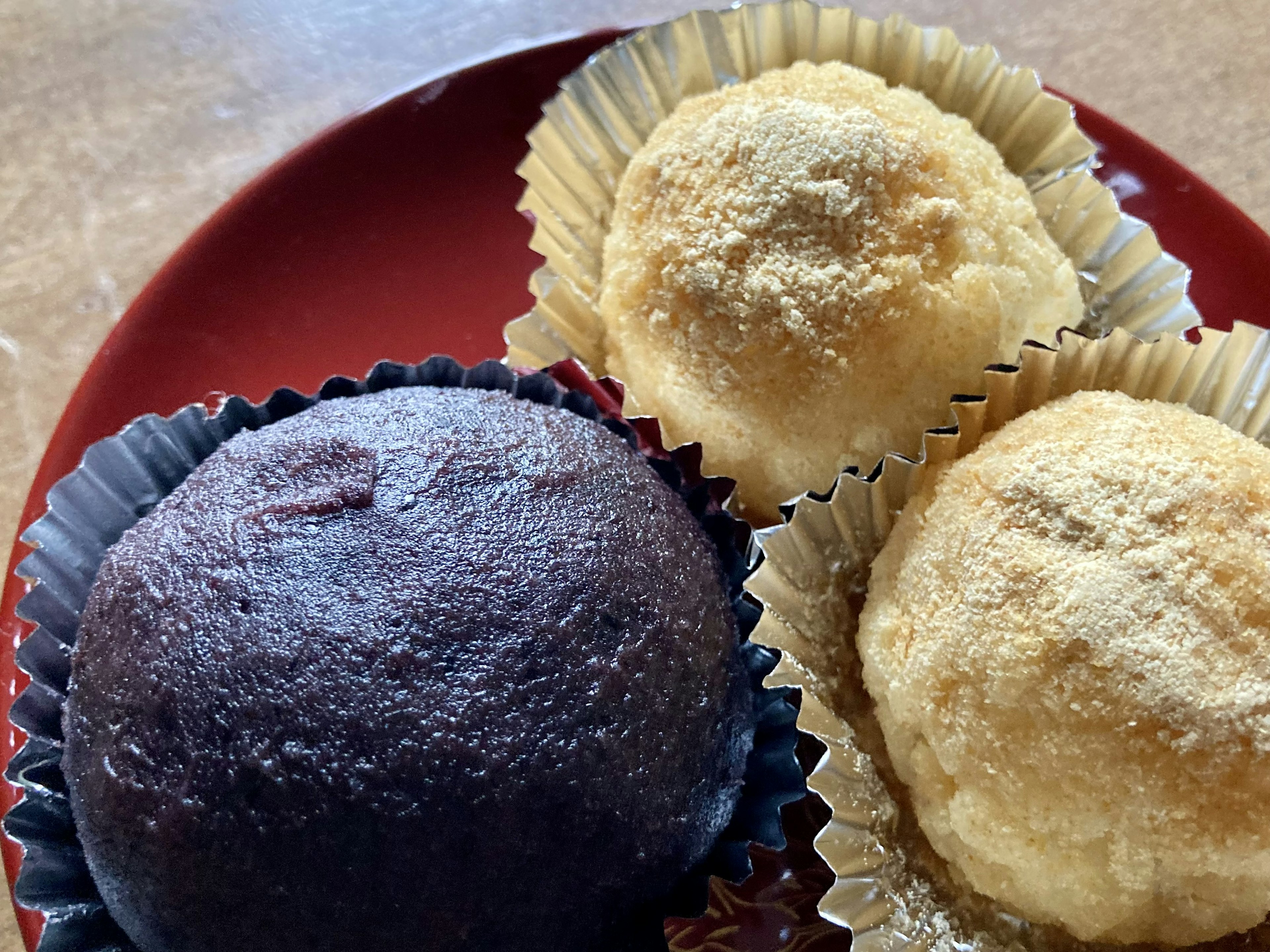 A black bun and two white rice cakes displayed on a red plate