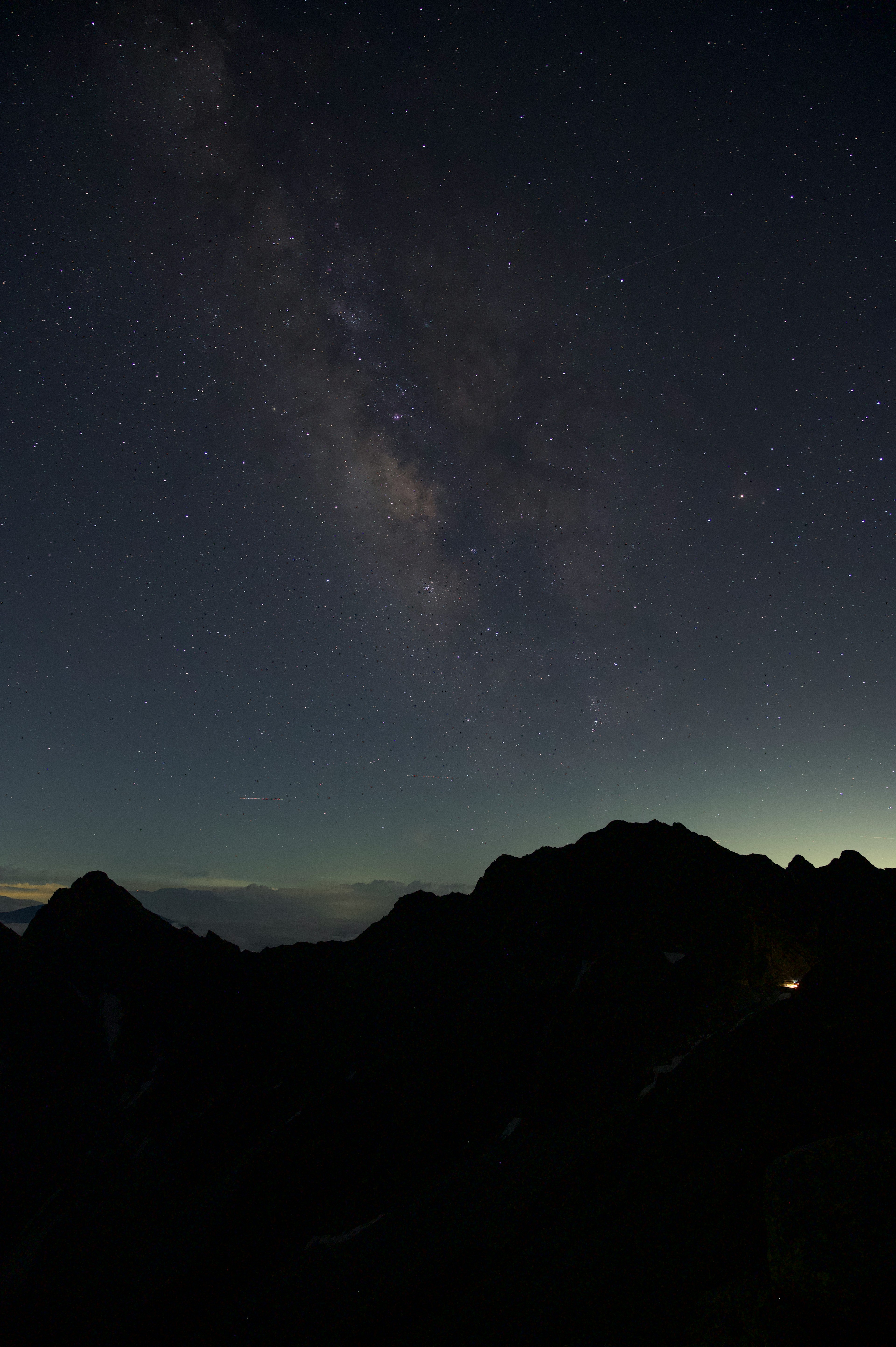 星空に広がる天の川と山々のシルエット