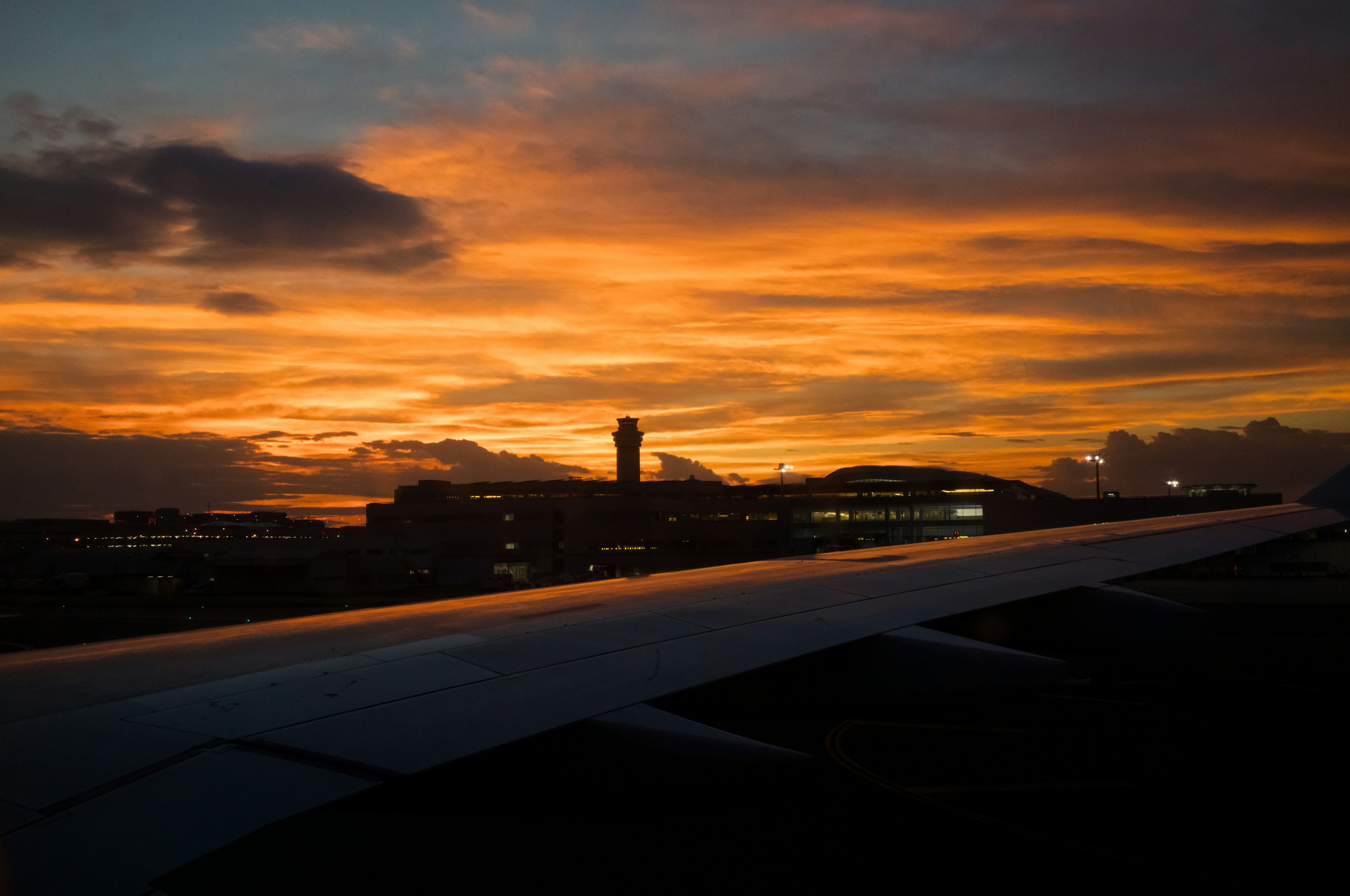 Sonnenuntergangshimmel mit Flughafenansicht Flugzeugflügel sichtbar