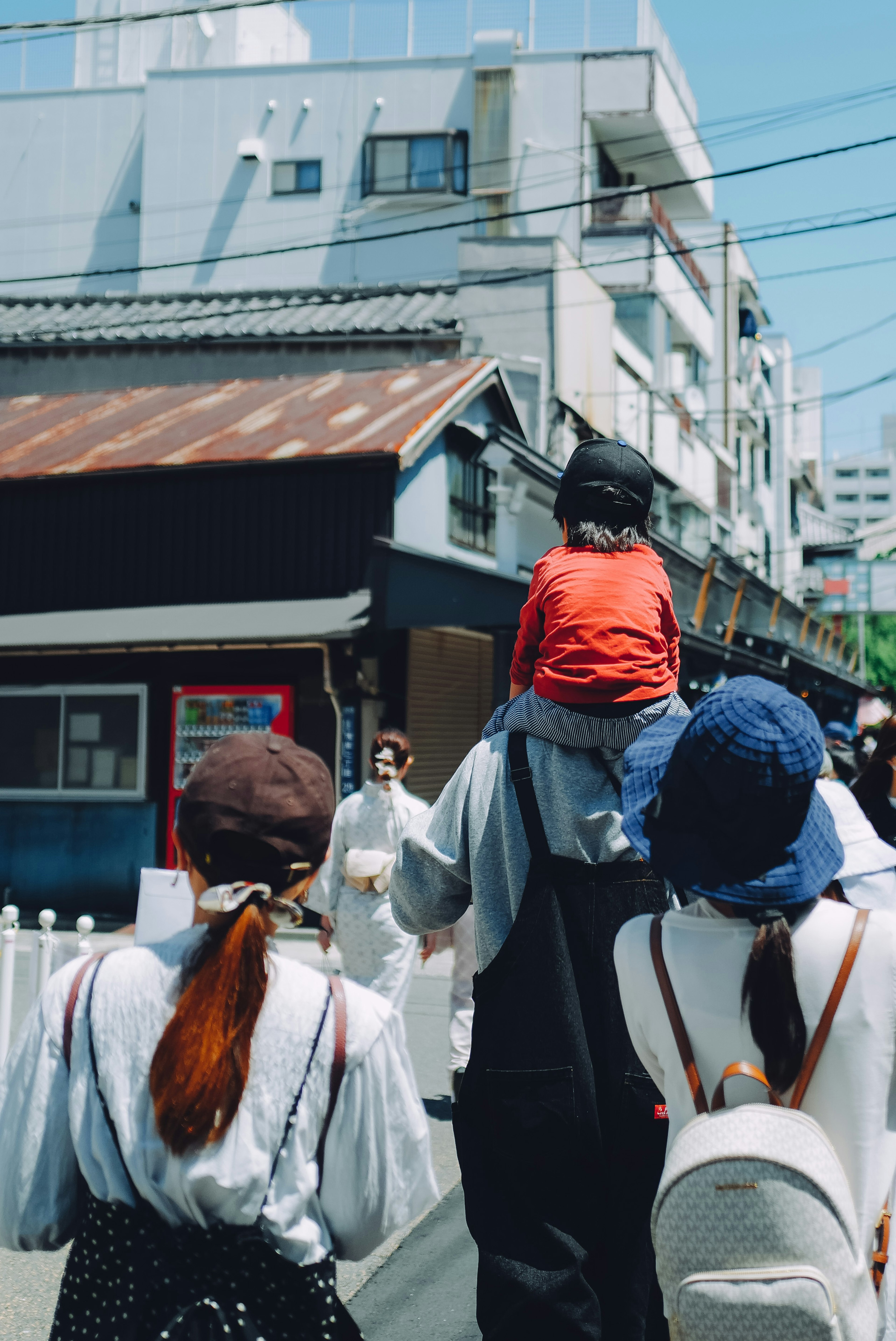 Personas caminando en la calle con un hombre cargando a un niño sobre sus hombros