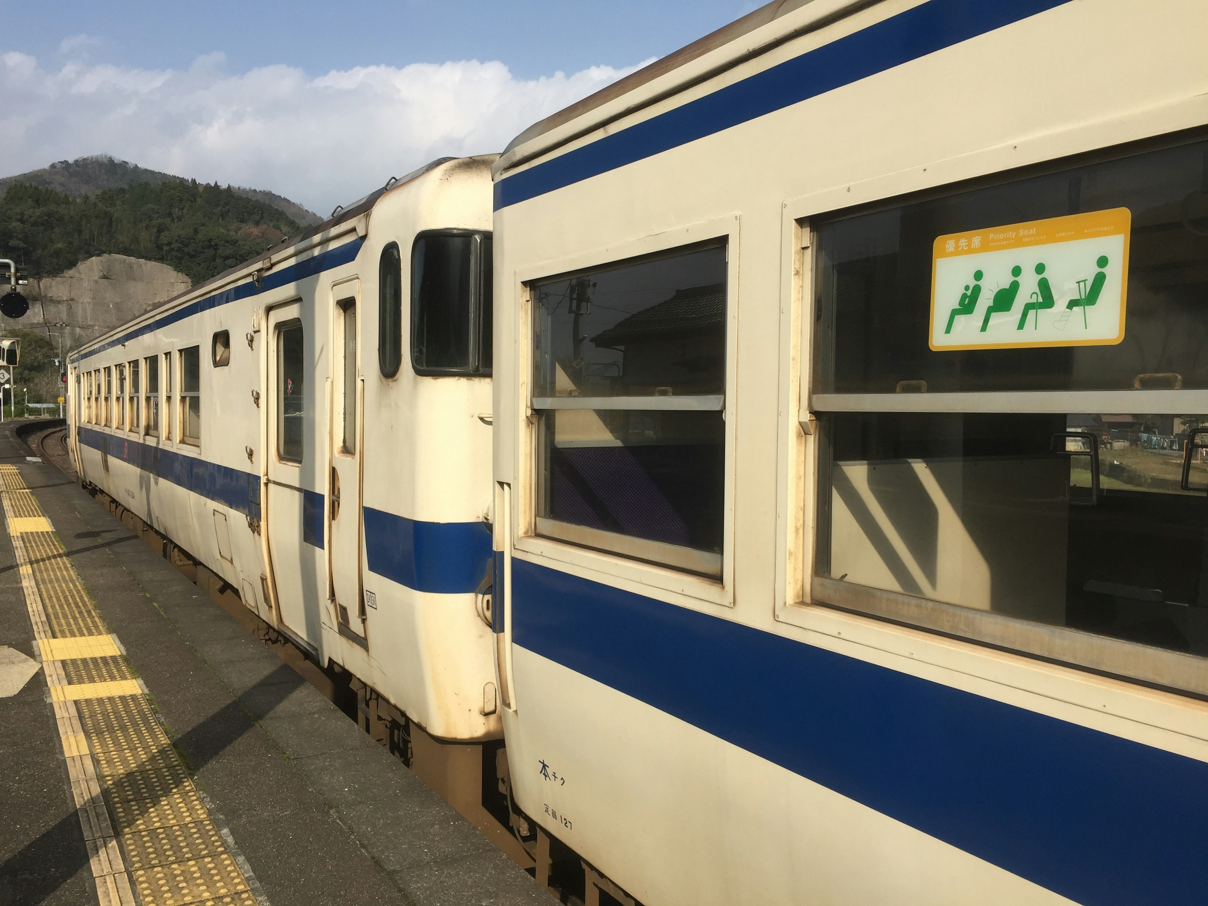 青いストライプの電車が駅のプラットフォームに停車している