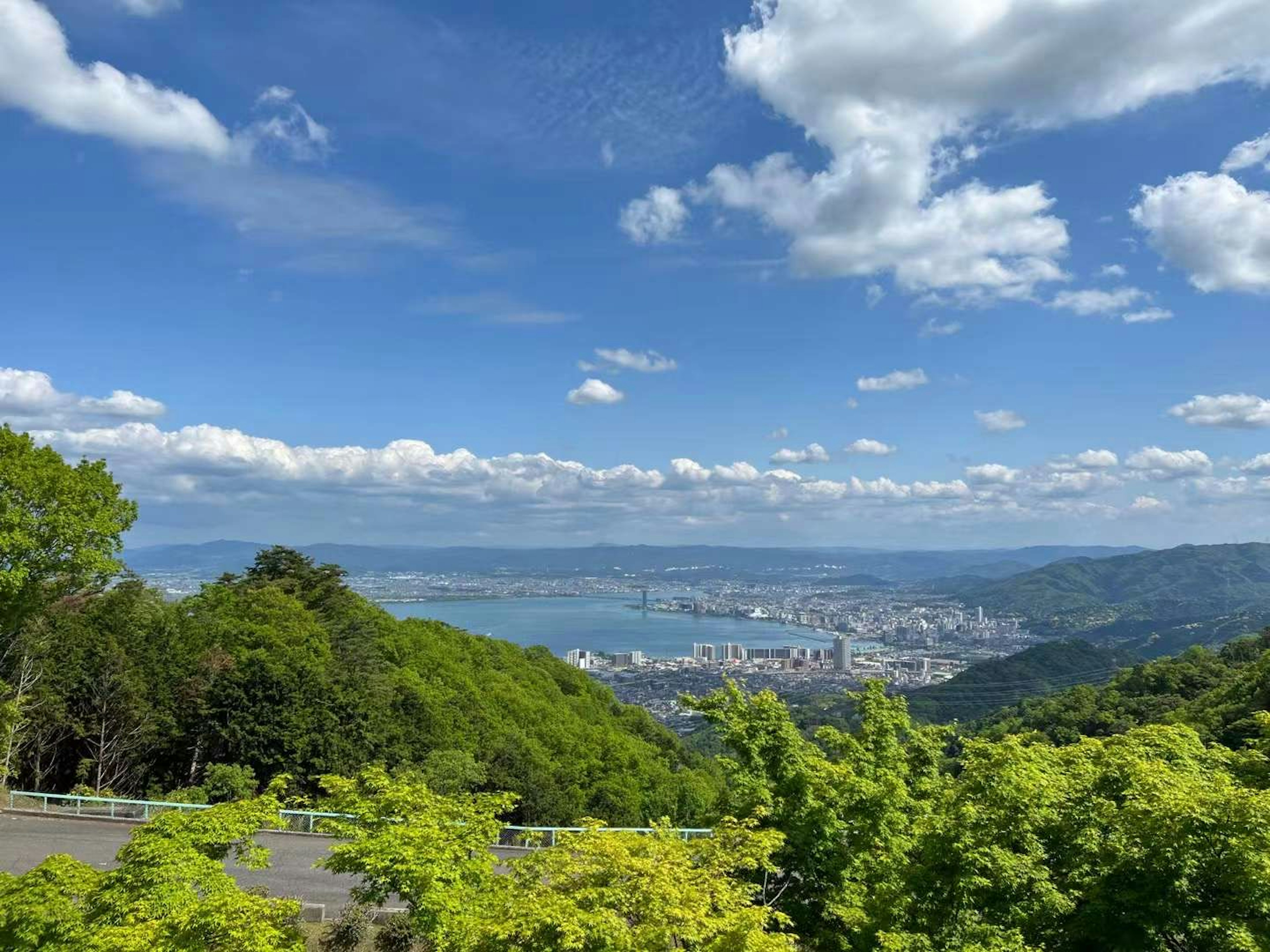 Mountain view with blue sky and clouds lush green trees and city landscape