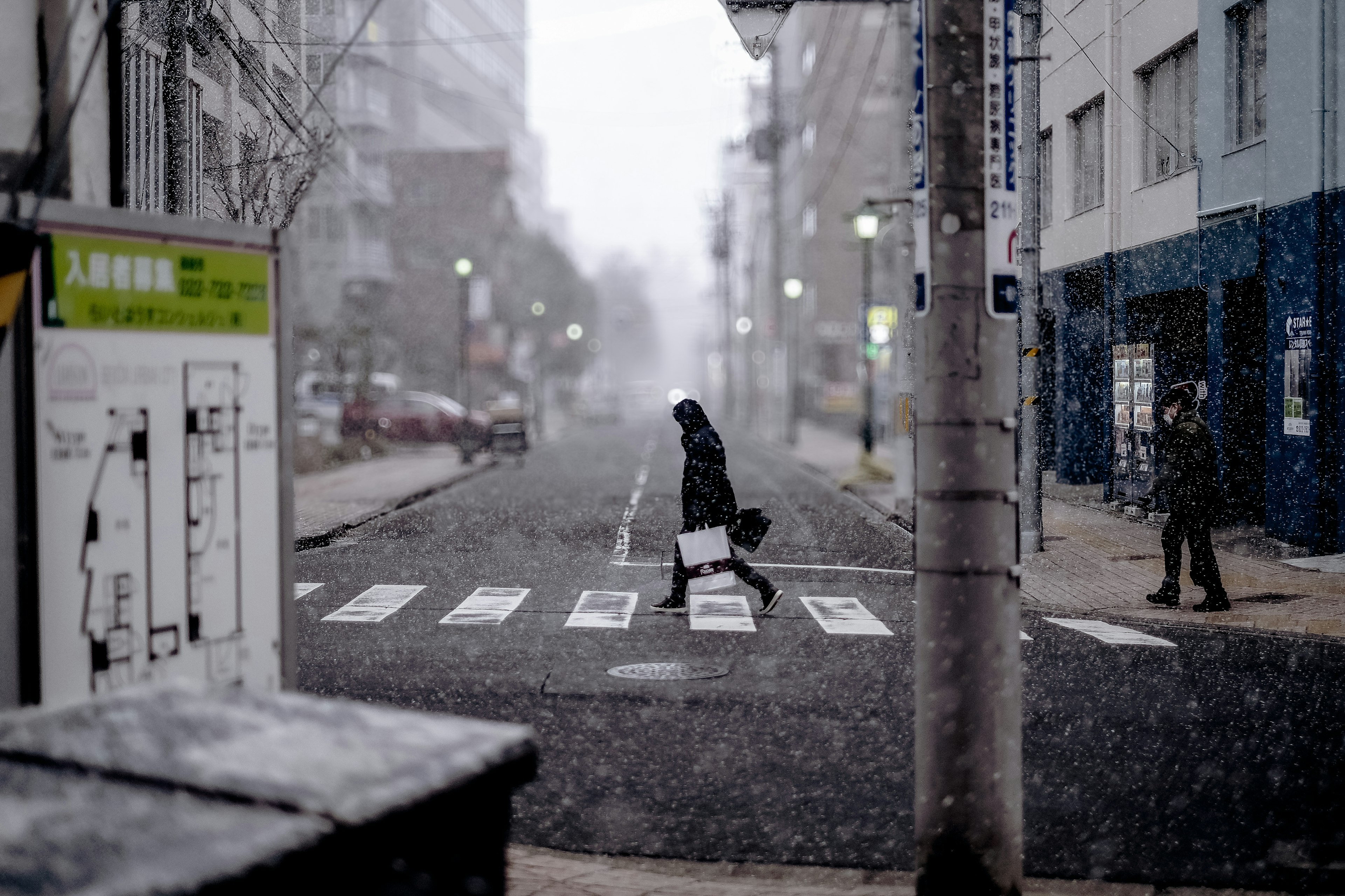 Persona cruzando un paso de peatones en un entorno urbano nevado