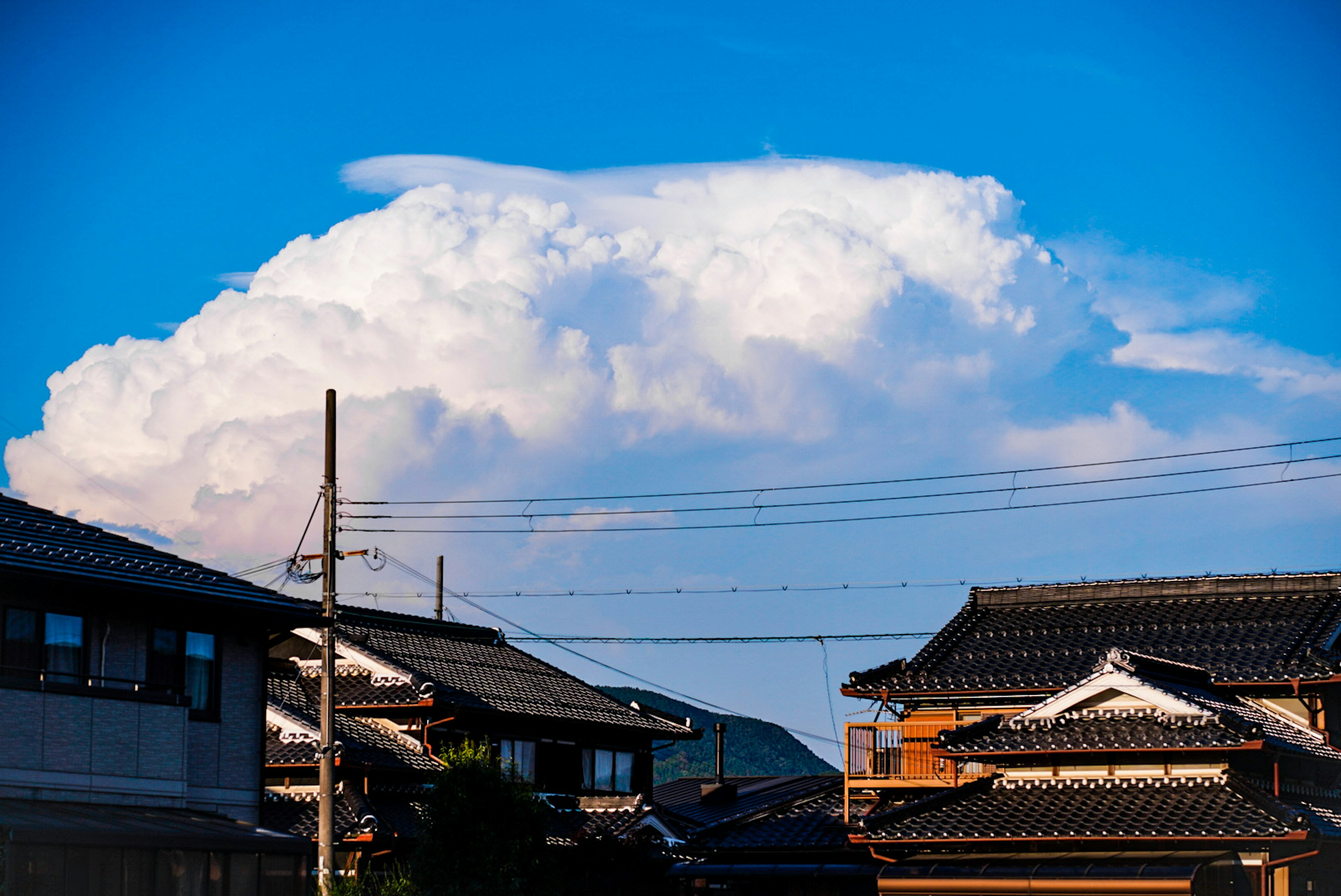 青い空に浮かぶ白い雲と日本の伝統的な家屋